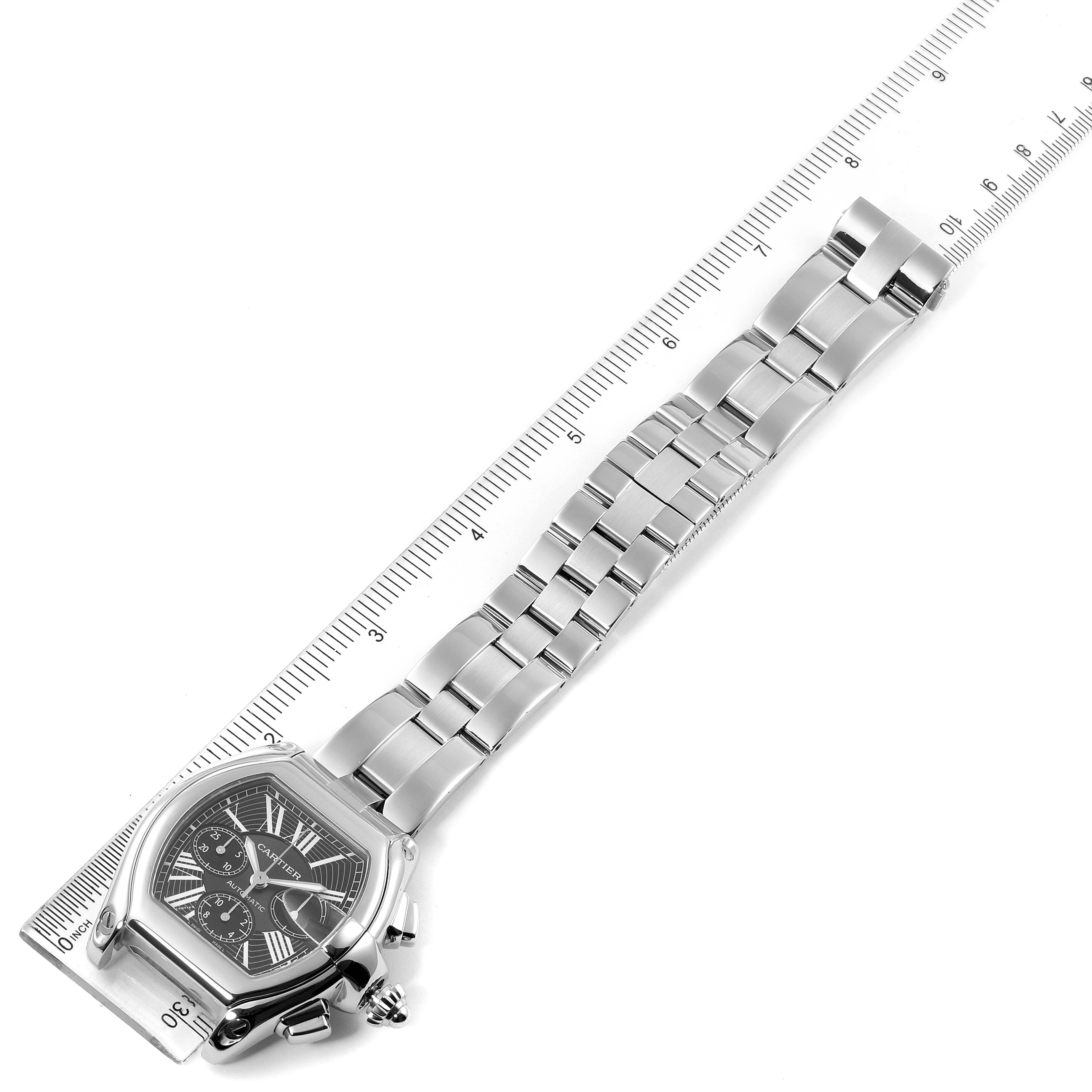 The Cartier Roadster W62020X6 Men
s Stainless Steel Black Dial W62020X6 Men
s Stainless Steel Black Dial watch is shown from a top-down angle with its face, bracelet, and clasp laid out next to a ruler.