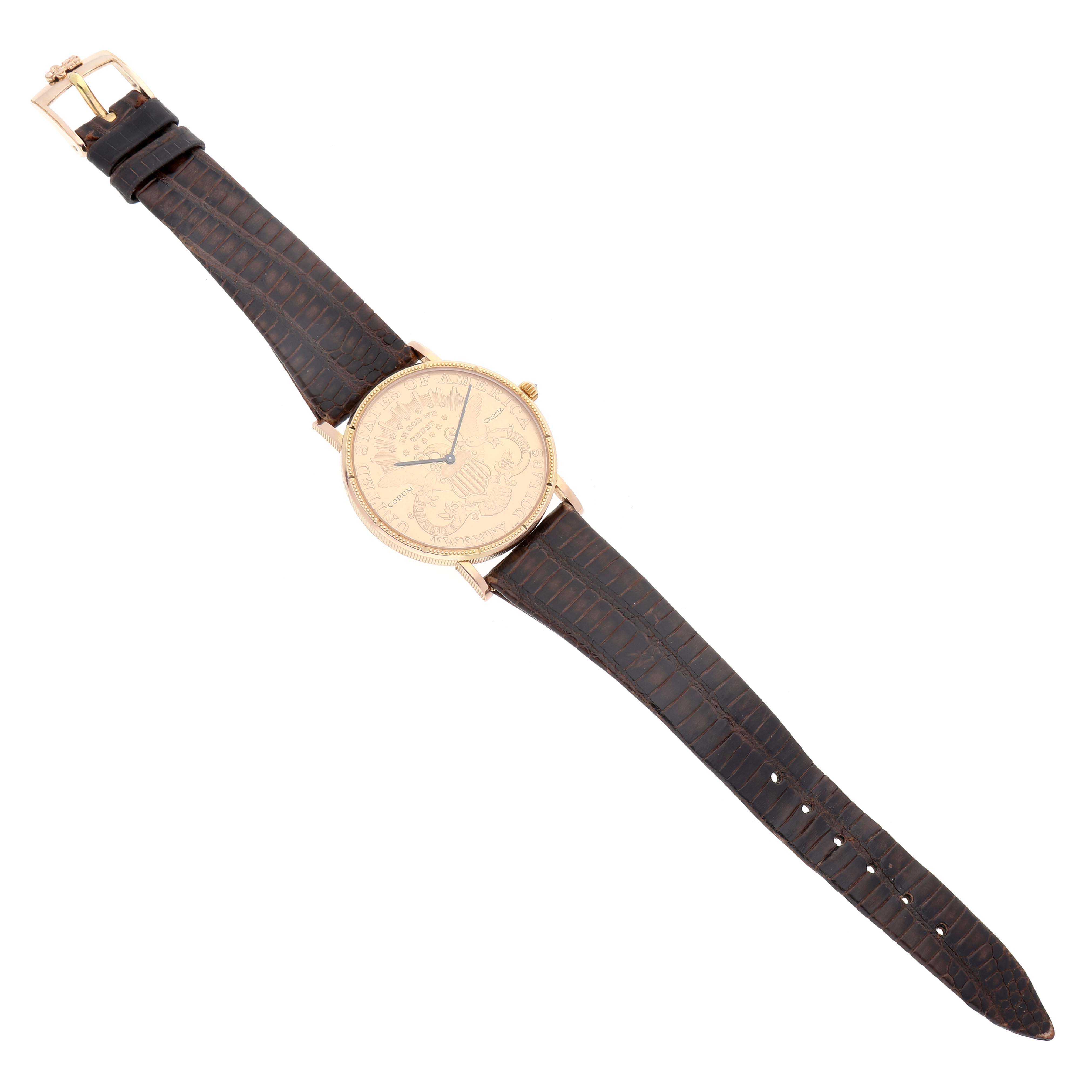 The Coin Watch by Corum is shown from a top-down angle, displaying the watch case, dial, and full leather strap.