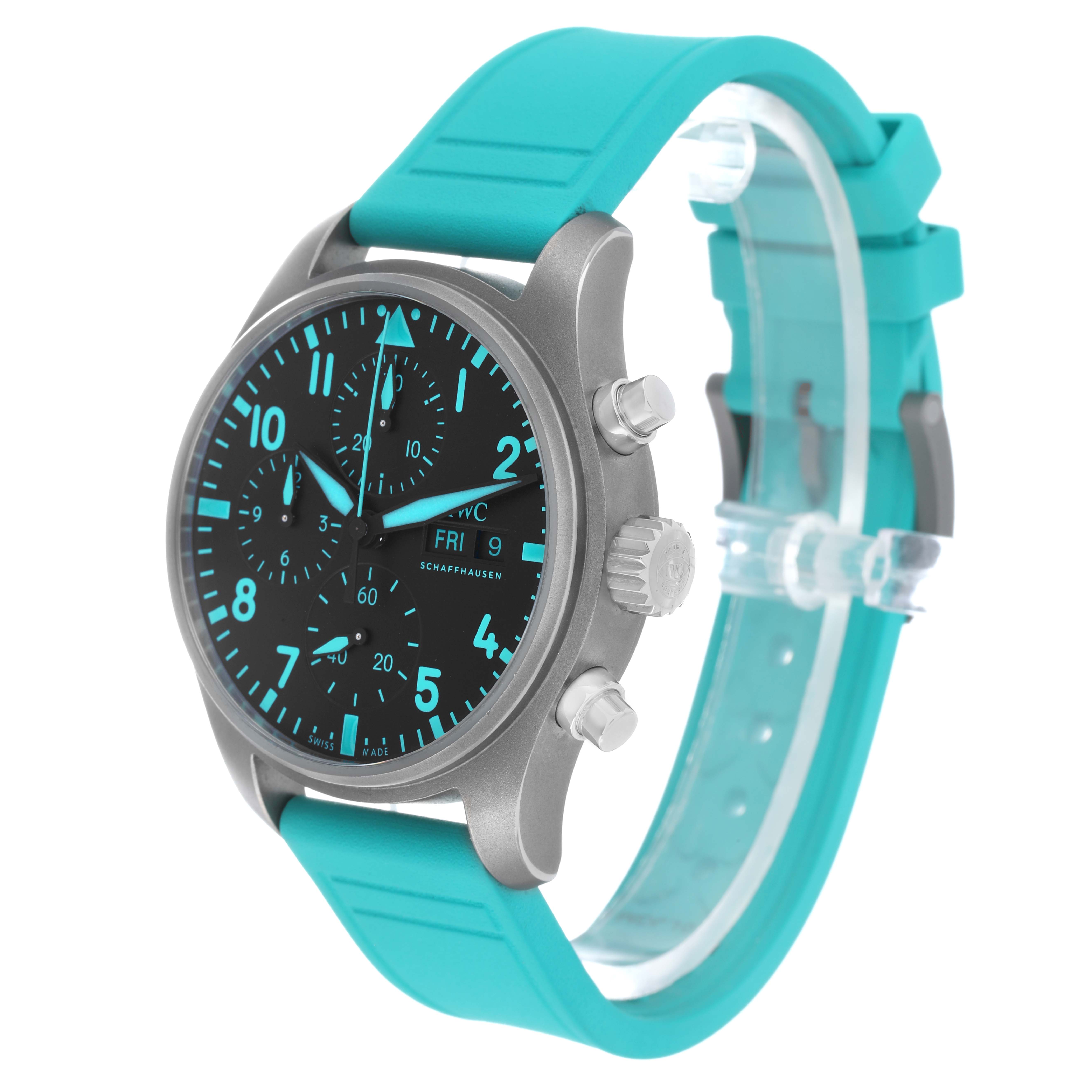 The IWC Pilot IW388108 Men's Titanium Black Dial watch is shown at a slight angle, displaying the dial, crown, pushers, and turquoise strap.