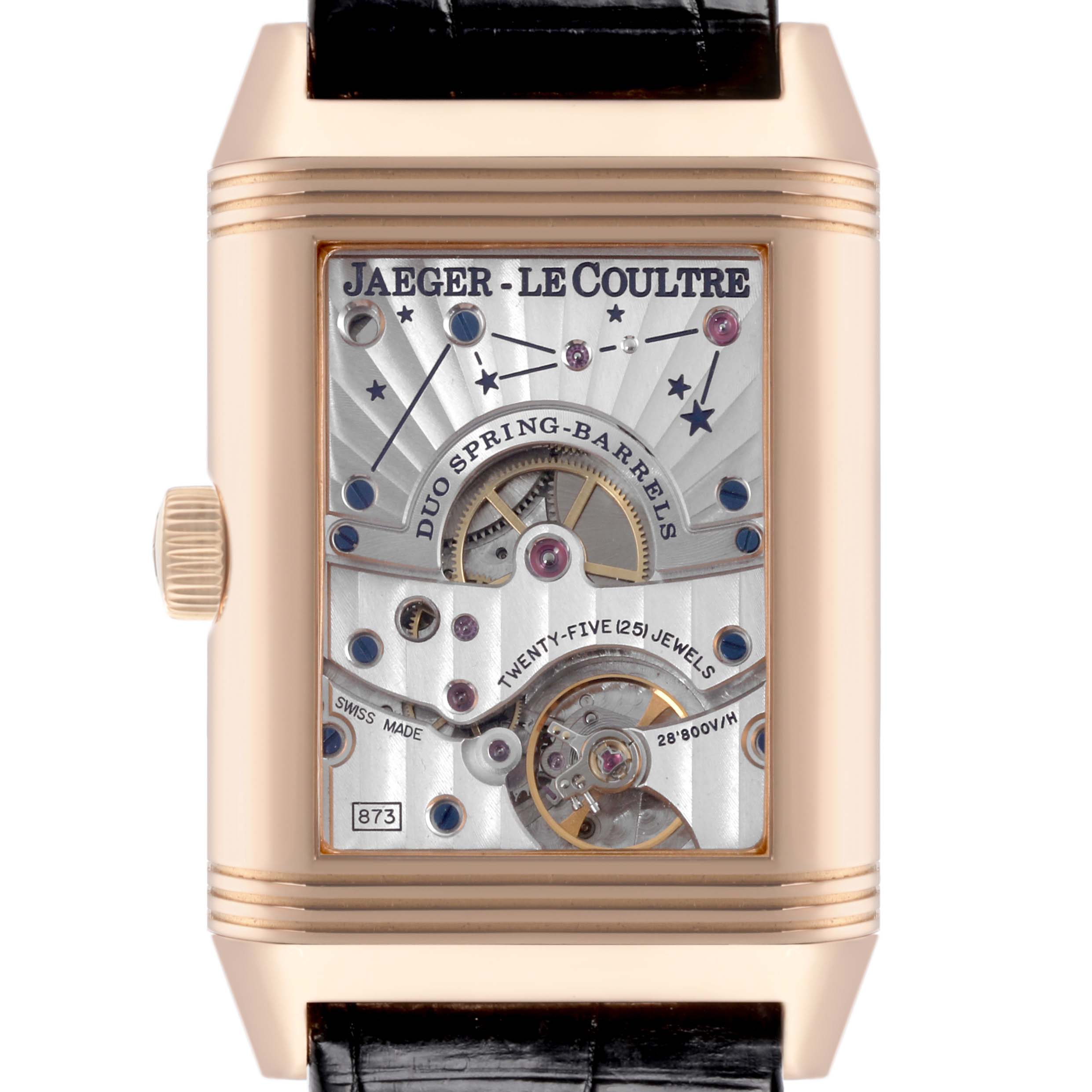 The Jaeger-LeCoultre Reverso watch is shown from the front, displaying its open mechanical movement with intricate detailing.