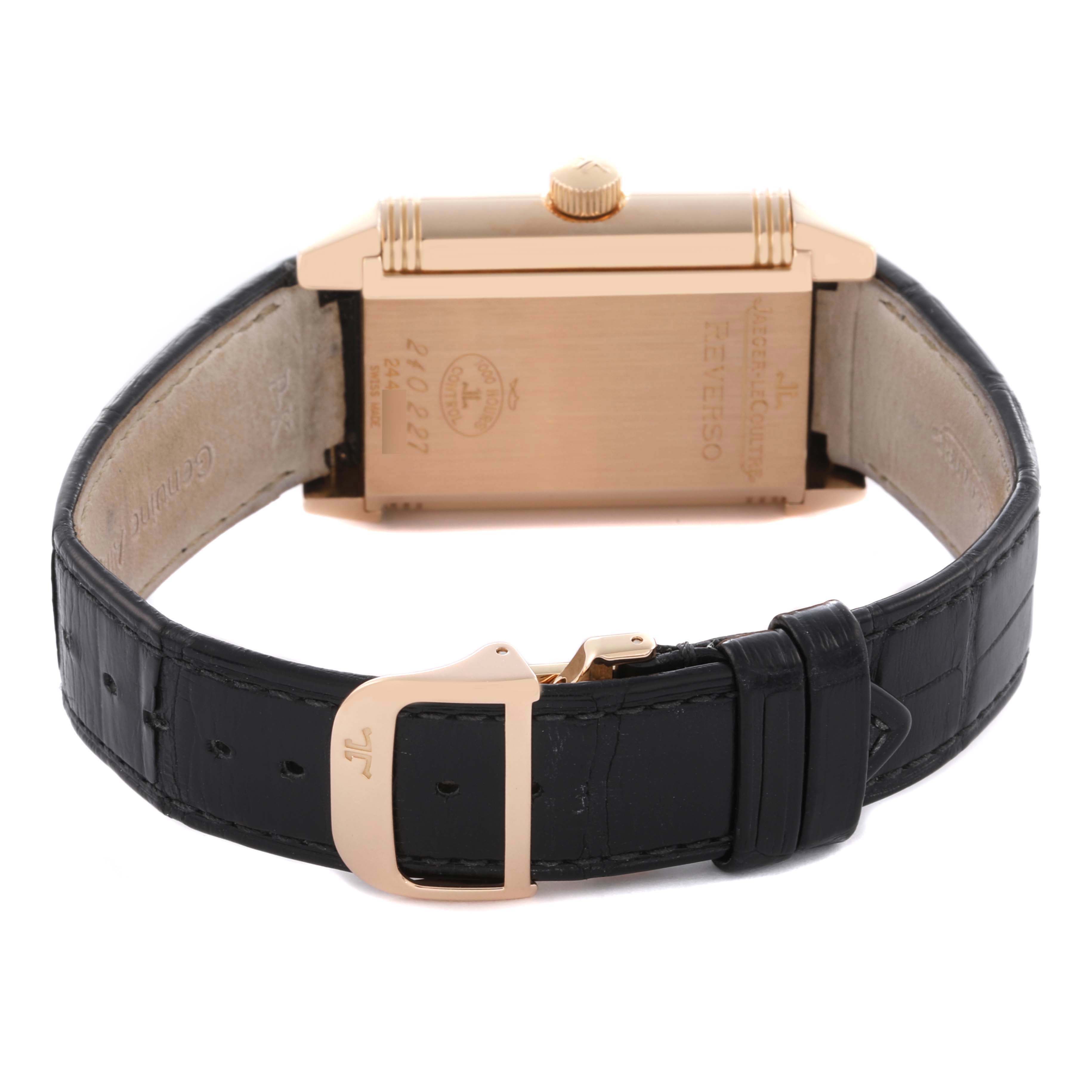 The image shows the back of a Jaeger-LeCoultre Reverso watch, highlighting the case back, crown, and black leather strap.