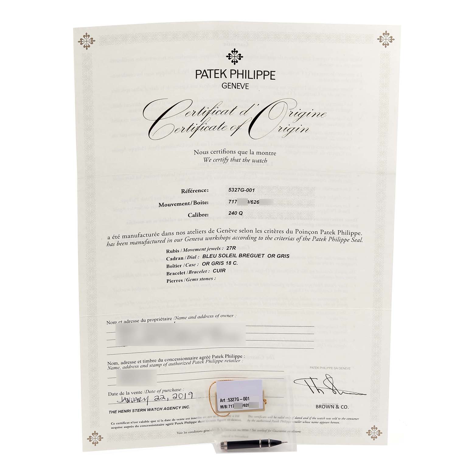 The image shows a Patek Philippe Complications 5327G-001 Men's White Gold Blue Dial 5327G-001 Men's White Gold Blue Dial model certificate and its tag, positioned from above.