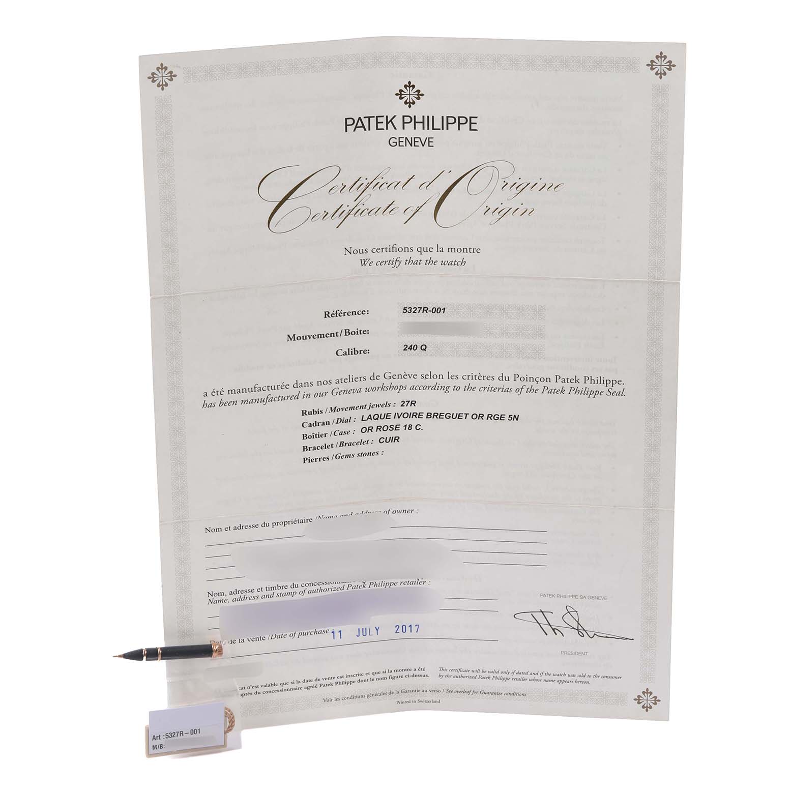 The image shows a Patek Philippe Complications 5327R-001 Men's Rose Gold White Dial 5327R-001 Men's Rose Gold White Dial certificate of origin, pen, and holder, with no watch visible.