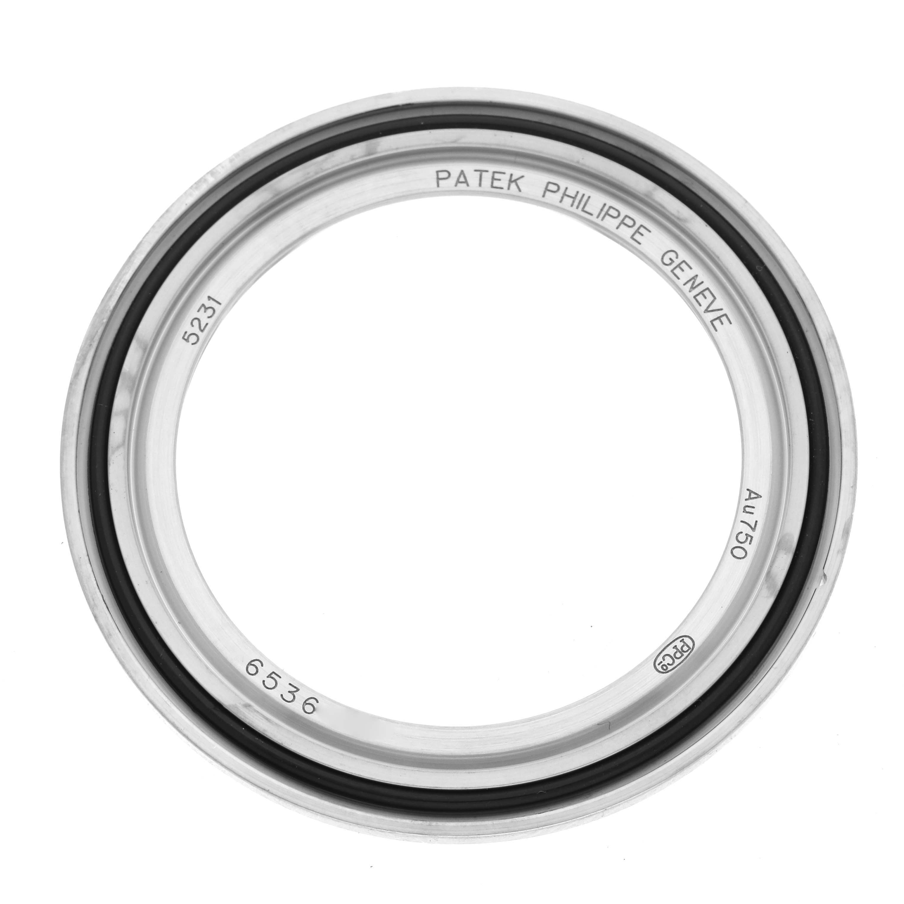 The image shows a Patek Philippe Complications 5231G-001 Men's White Gold Silver Dial 5231G-001 Men's White Gold Silver Dial watch bezel from a top-down view, highlighting its circular design and inscriptions.