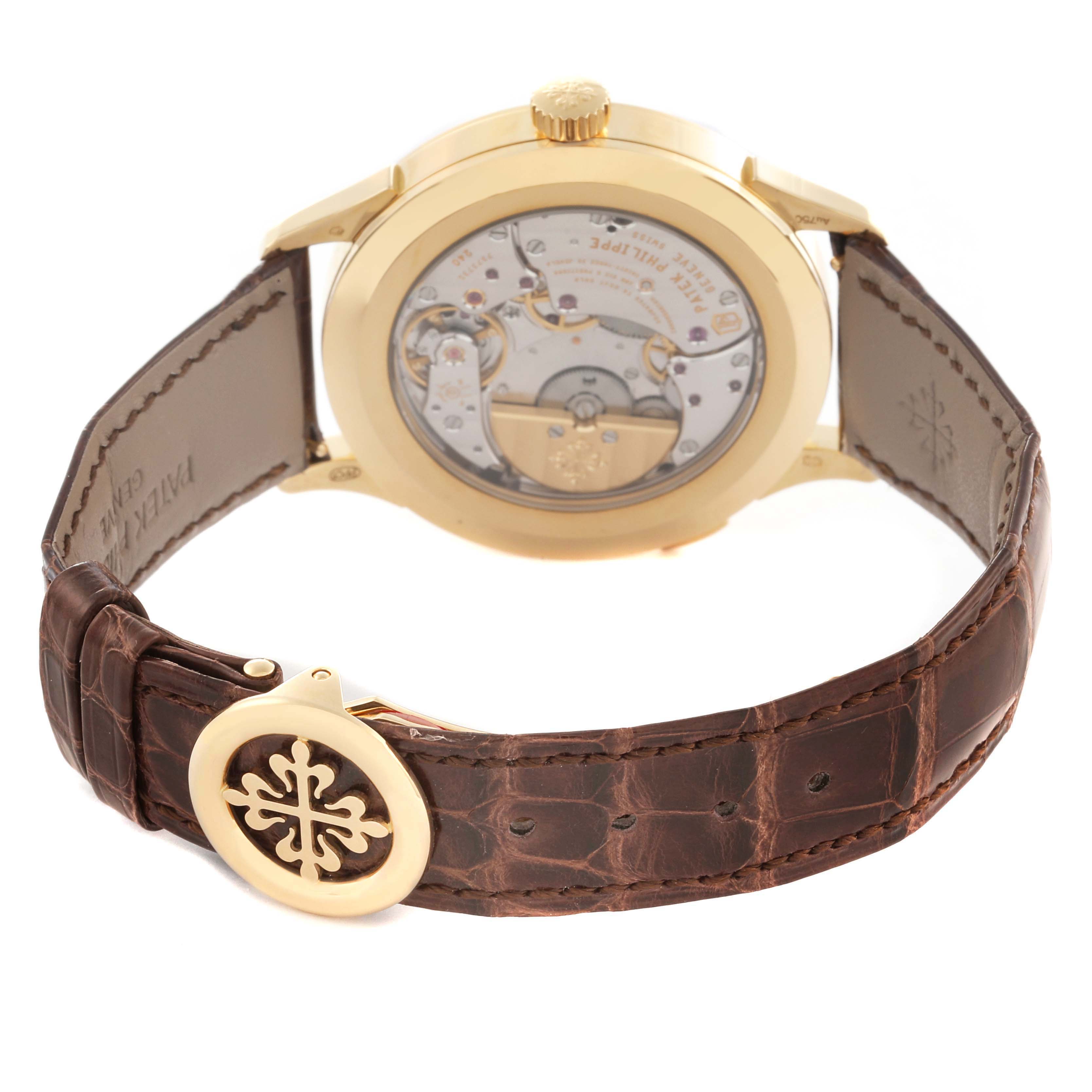 The image shows the back view of a Patek Philippe Complications 5231J-001 Men's Yellow Gold Silver Dial 5231J-001 Men's Yellow Gold Silver Dial watch, highlighting the movement and brown leather strap.