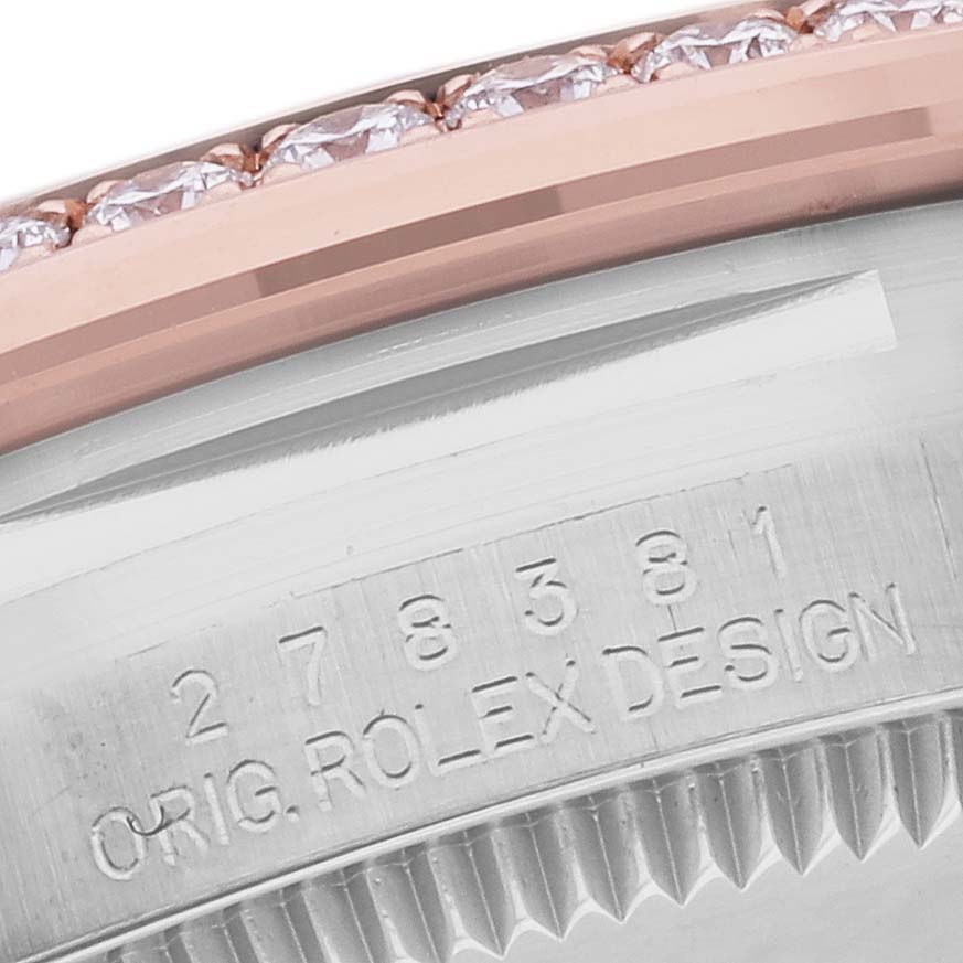 The image shows a close-up of the Rolex Mid-Size 278381 Women's Steel and Gold (two tone) Pink Dial 278381 Women's Steel and Gold (two tone) Pink Dial model's bezel and etched side, highlighting diamonds and the engraved design code.