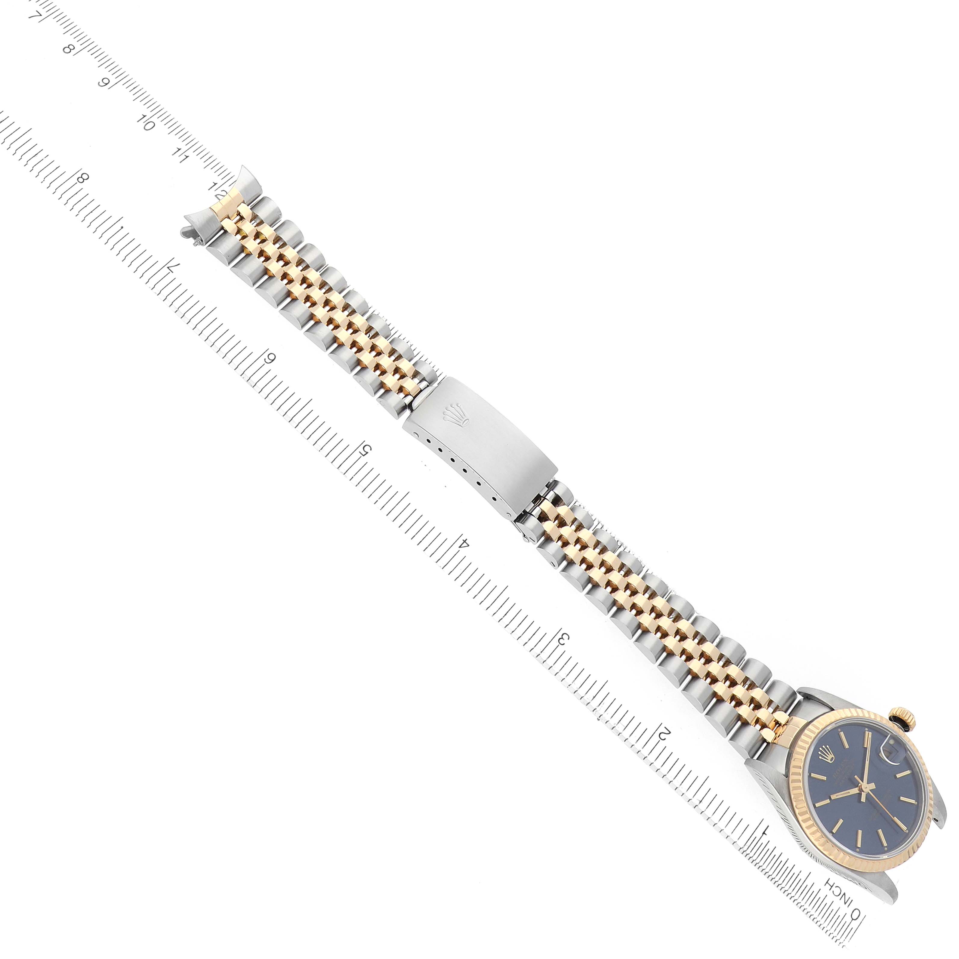 The Rolex Mid-Size 68273 Women's Steel and Gold (two tone) Blue Dial watch is shown from a top-down angle, displaying the face, bezel, bracelet, and clasp with a ruler for scale.