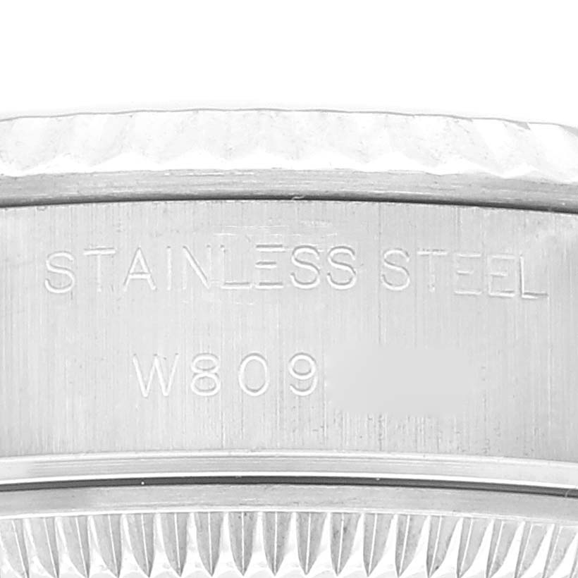 This close-up image shows a partial view of the side of a Rolex Datejust 69174 Women's Stainless Steel Black Dial 69174 Women's Stainless Steel Black Dial watch, focusing on the engraving "STAINLESS STEEL" and a code.