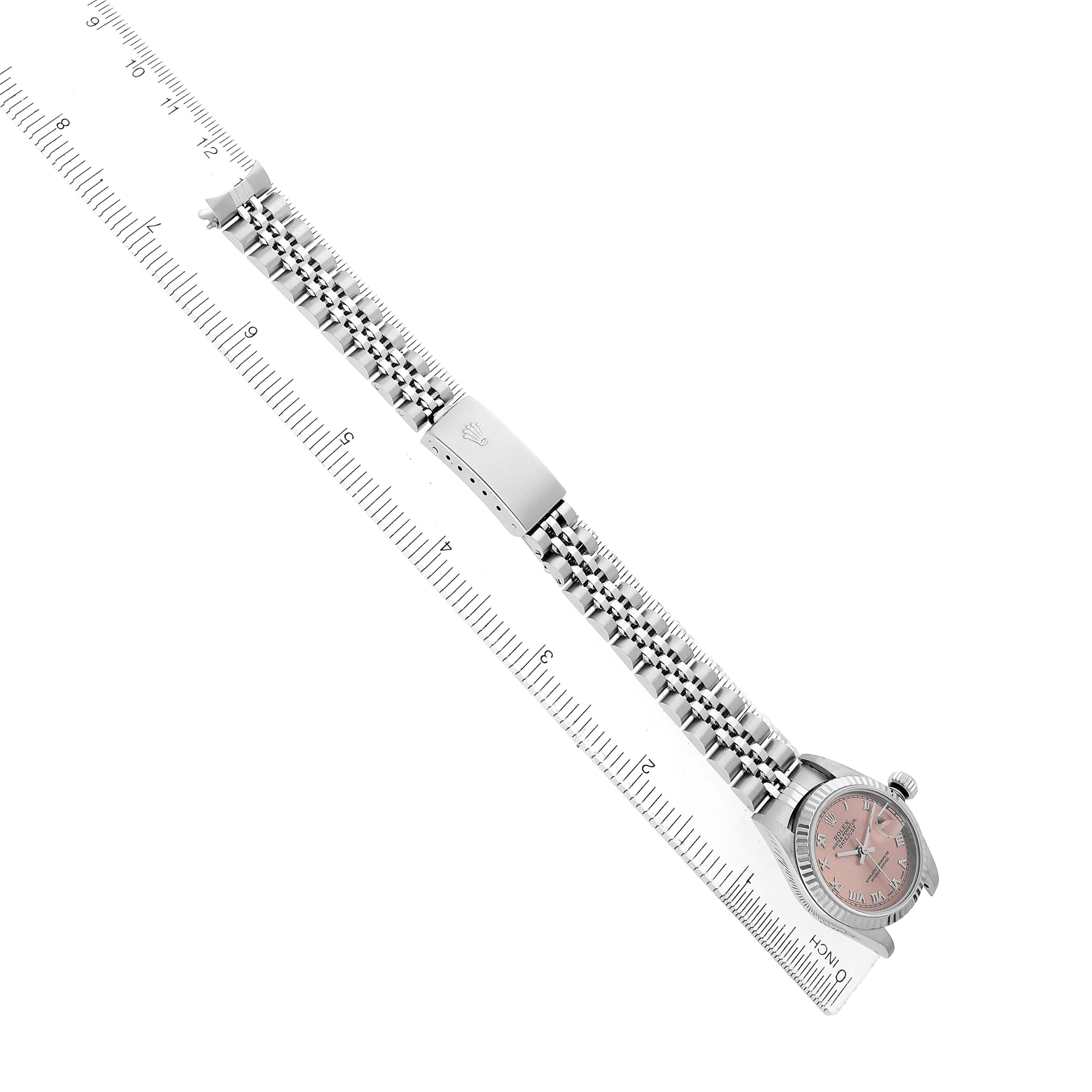 The Rolex Datejust 79174 Women's Stainless Steel Pink Dial watch is displayed diagonally, showing the bracelet, clasp, and partially the pink dial face, alongside a measuring ruler.
