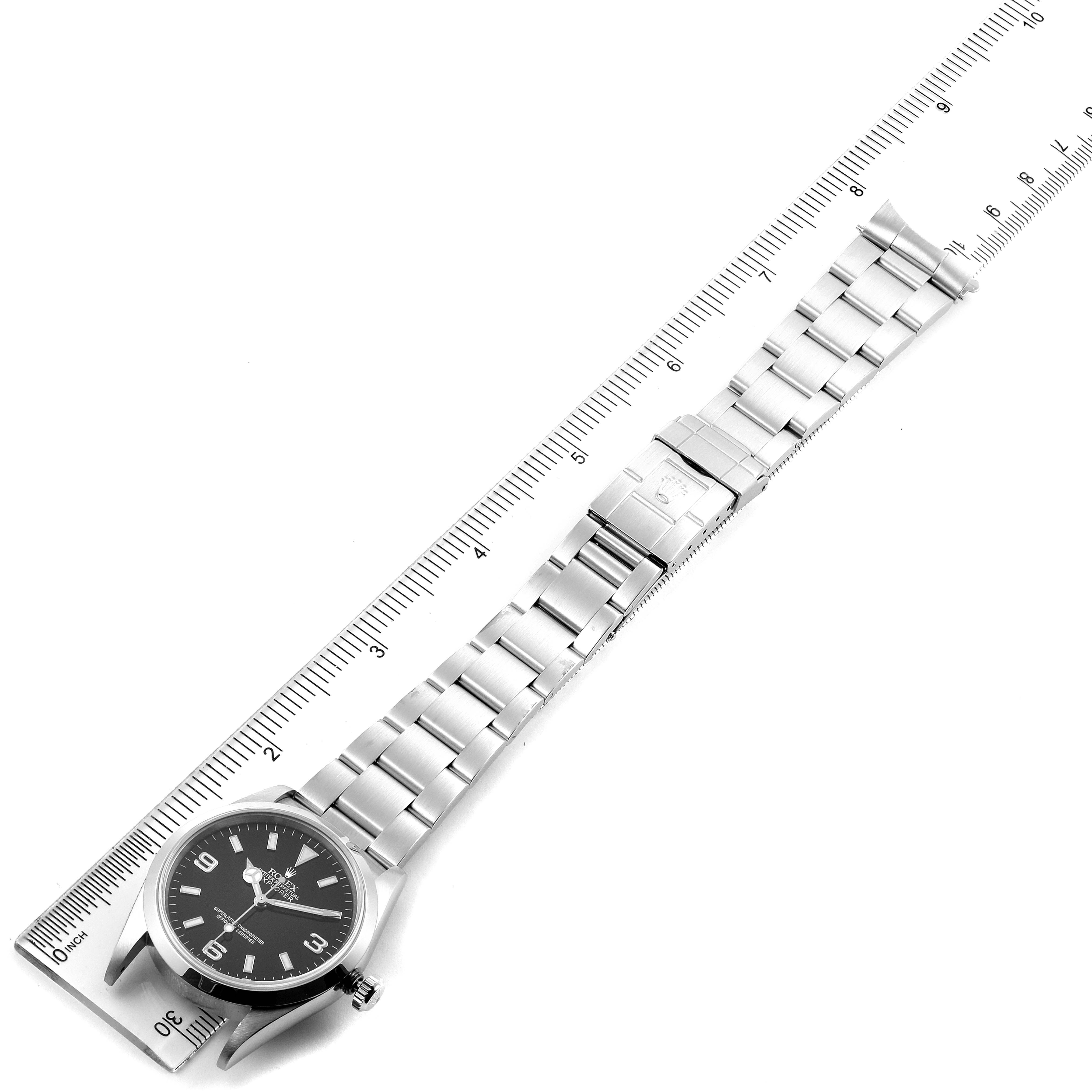 The image shows a Rolex Explorer 14270 Men
s Stainless Steel Black Dial 14270 Men
s Stainless Steel Black Dial watch laid flat with a stainless steel bracelet, positioned next to a ruler for size reference.