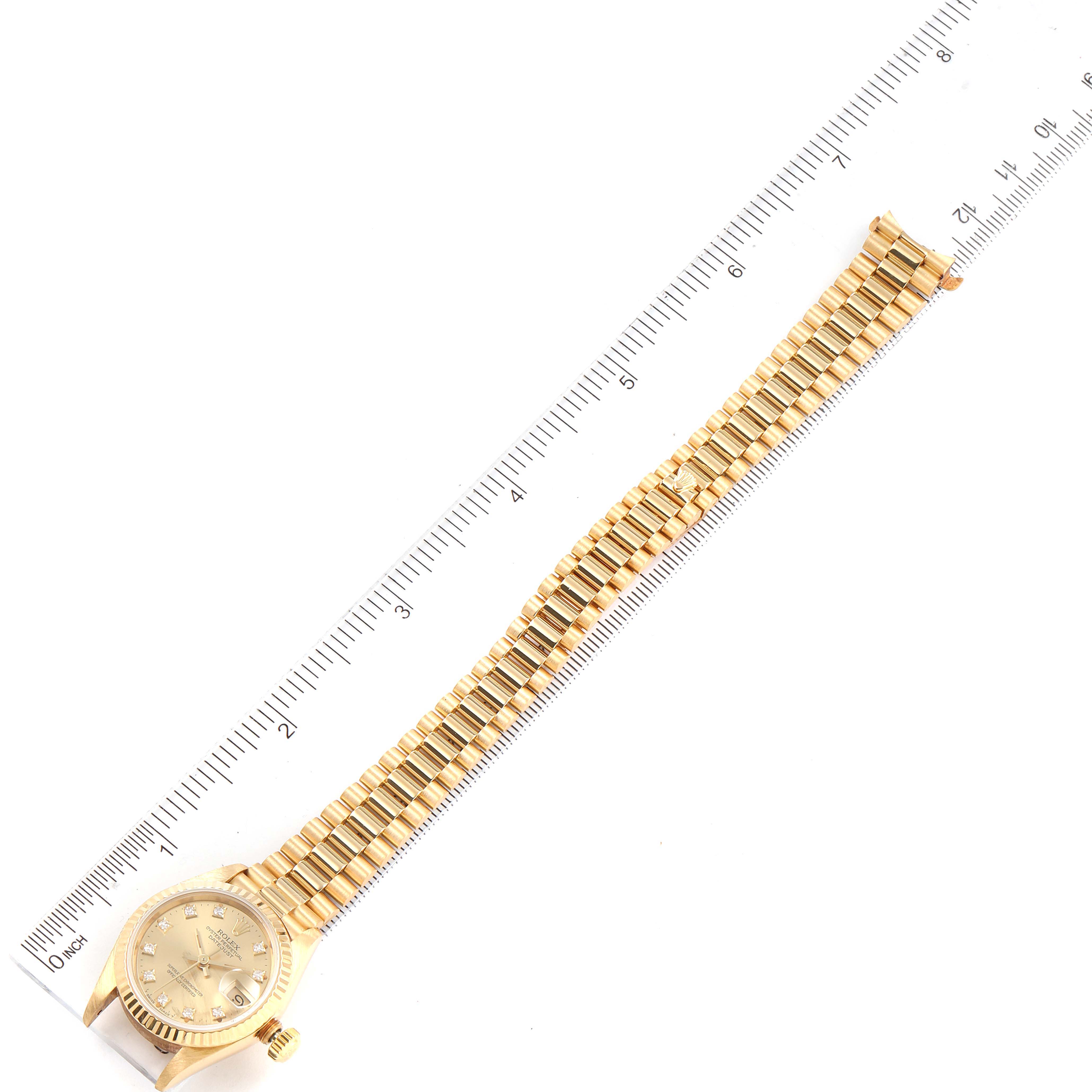 This image shows a full view of a Rolex President 69178 Women's Yellow Gold Champagne Dial 69178 Women's Yellow Gold Champagne Dial model watch and its band against a ruler for scale.