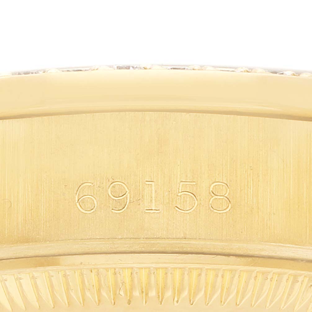 The image shows the side of a Rolex President 69158 Women's Yellow Gold Champagne Dial model watch, highlighting the engraved model number and part of the fluted bezel.