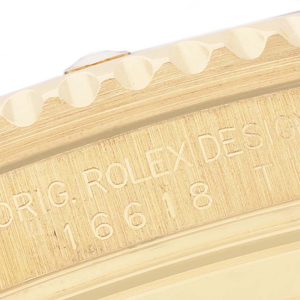 This image shows a close-up of the side of a Rolex Submariner 16618 Men's Yellow Gold Blue Dial 16618 Men's Yellow Gold Blue Dial, focusing on the engraved bezel edge.
