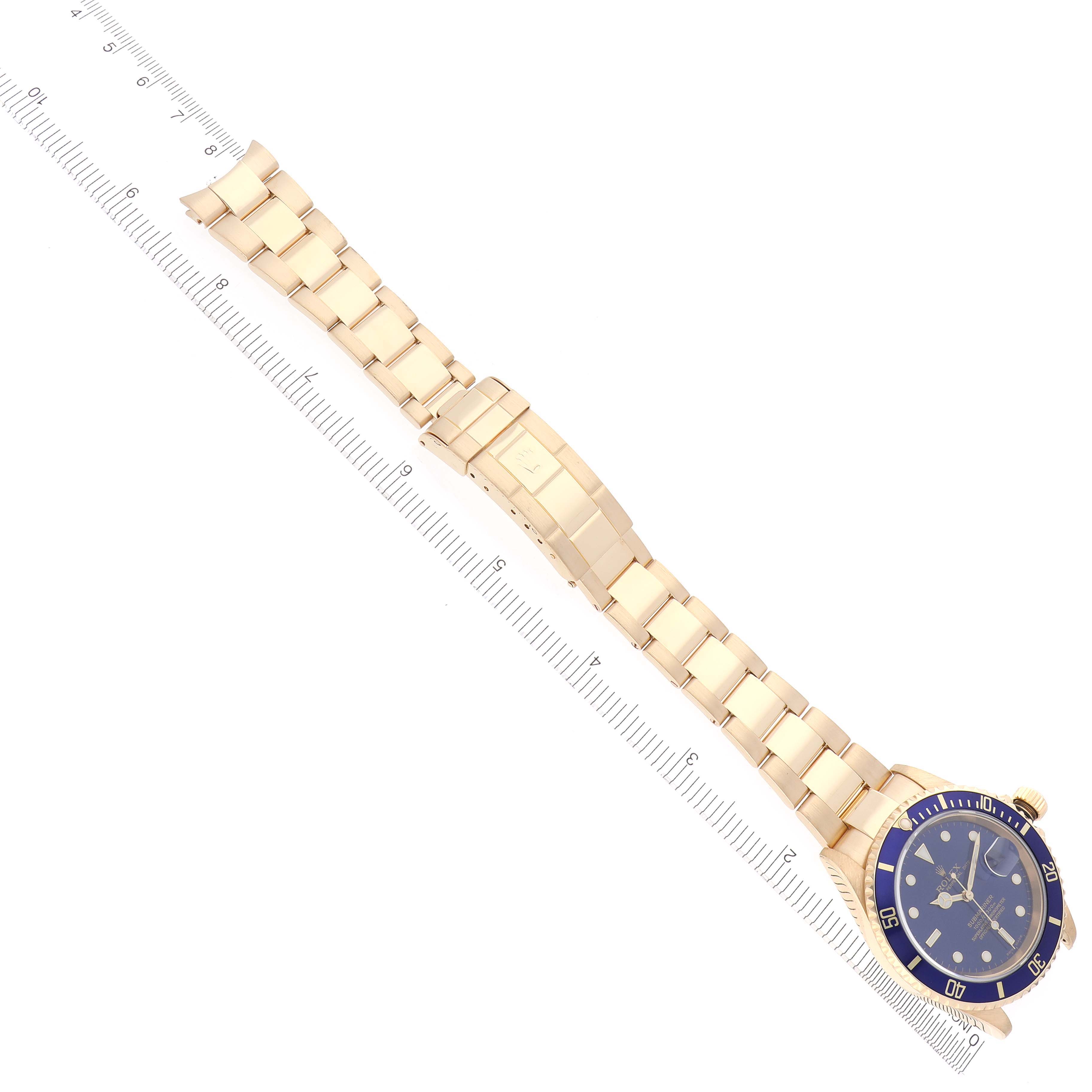 The Rolex Submariner 16618 Men's Yellow Gold Blue Dial 16618 Men's Yellow Gold Blue Dial is shown at an overhead angle, displaying the bracelet and face alongside a ruler for scale.