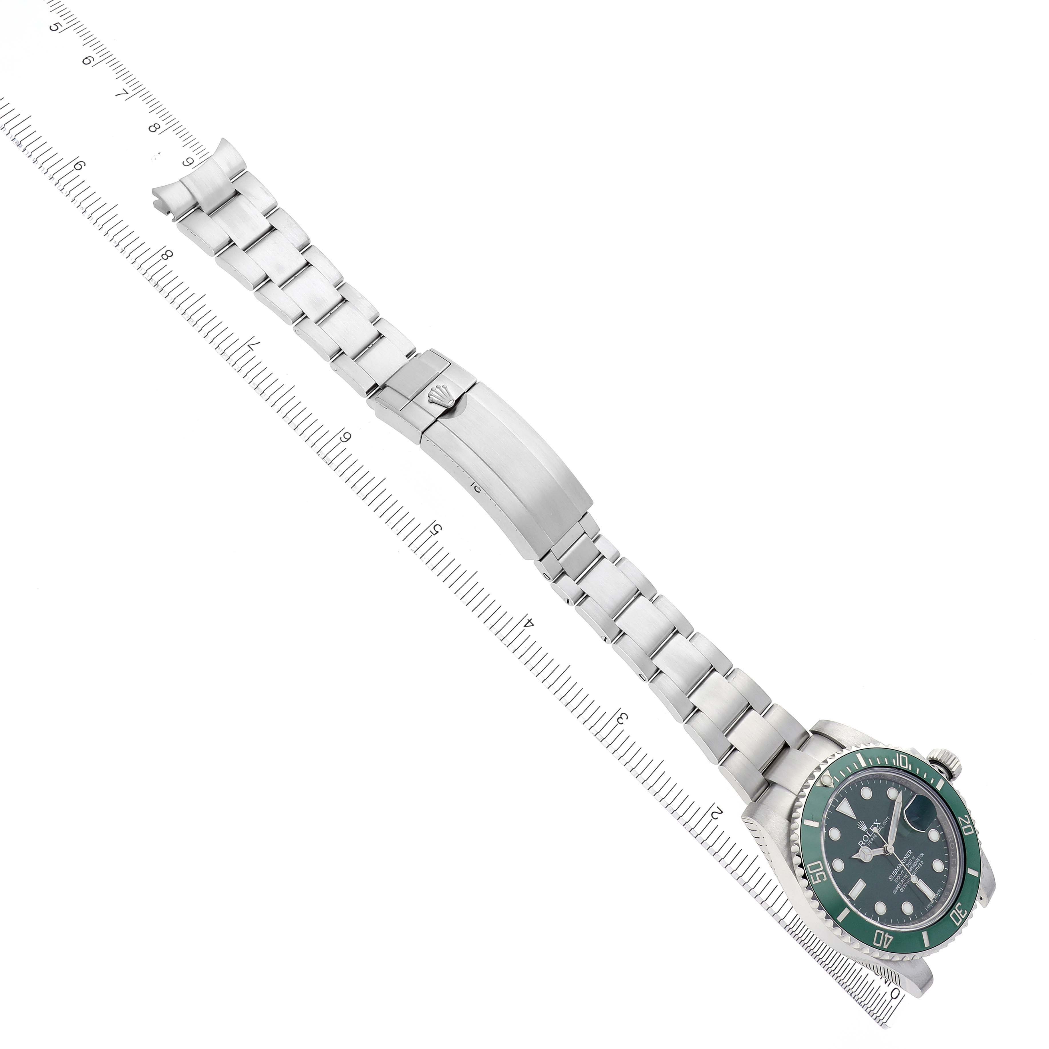 The Rolex Submariner 116610LV Men's Stainless Steel Green Dial 116610LV Men's Stainless Steel Green Dial watch is shown from a top view, displaying the face, bracelet, and clasp alongside a measuring ruler.
