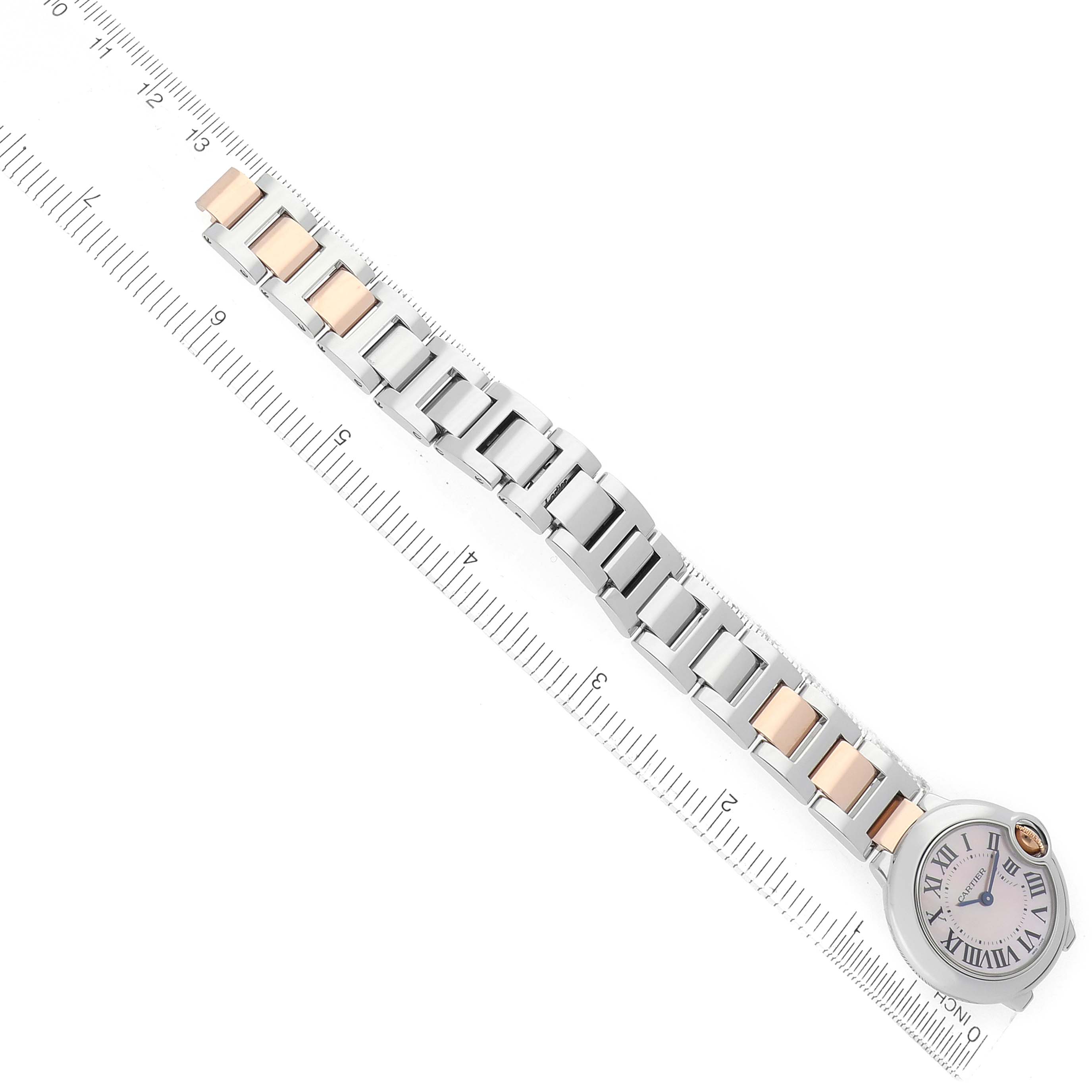 The Cartier Ballon Bleu W6920034 Women's Steel and Gold (two tone) Mother of Pearl Dial watch is shown from an angled top-down view, displaying its full bracelet and face next to a ruler for scale.