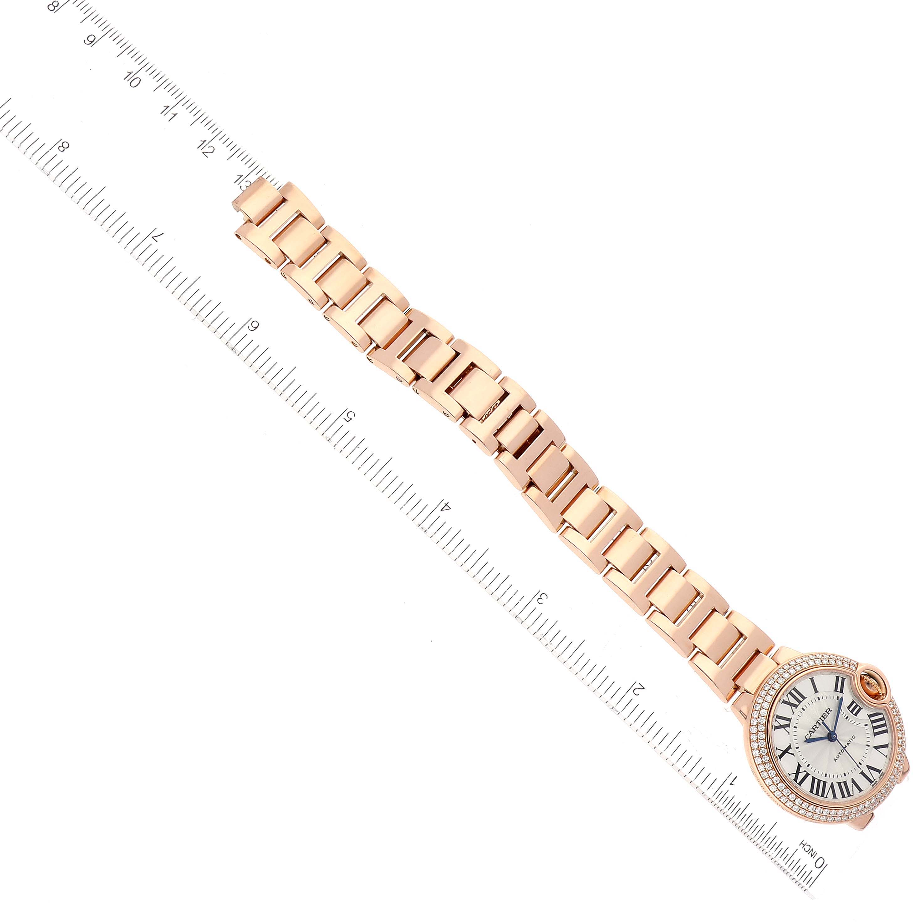 The image shows the Ballon Bleu model by Cartier laid flat with a gold bracelet and a measuring ruler positioned alongside.