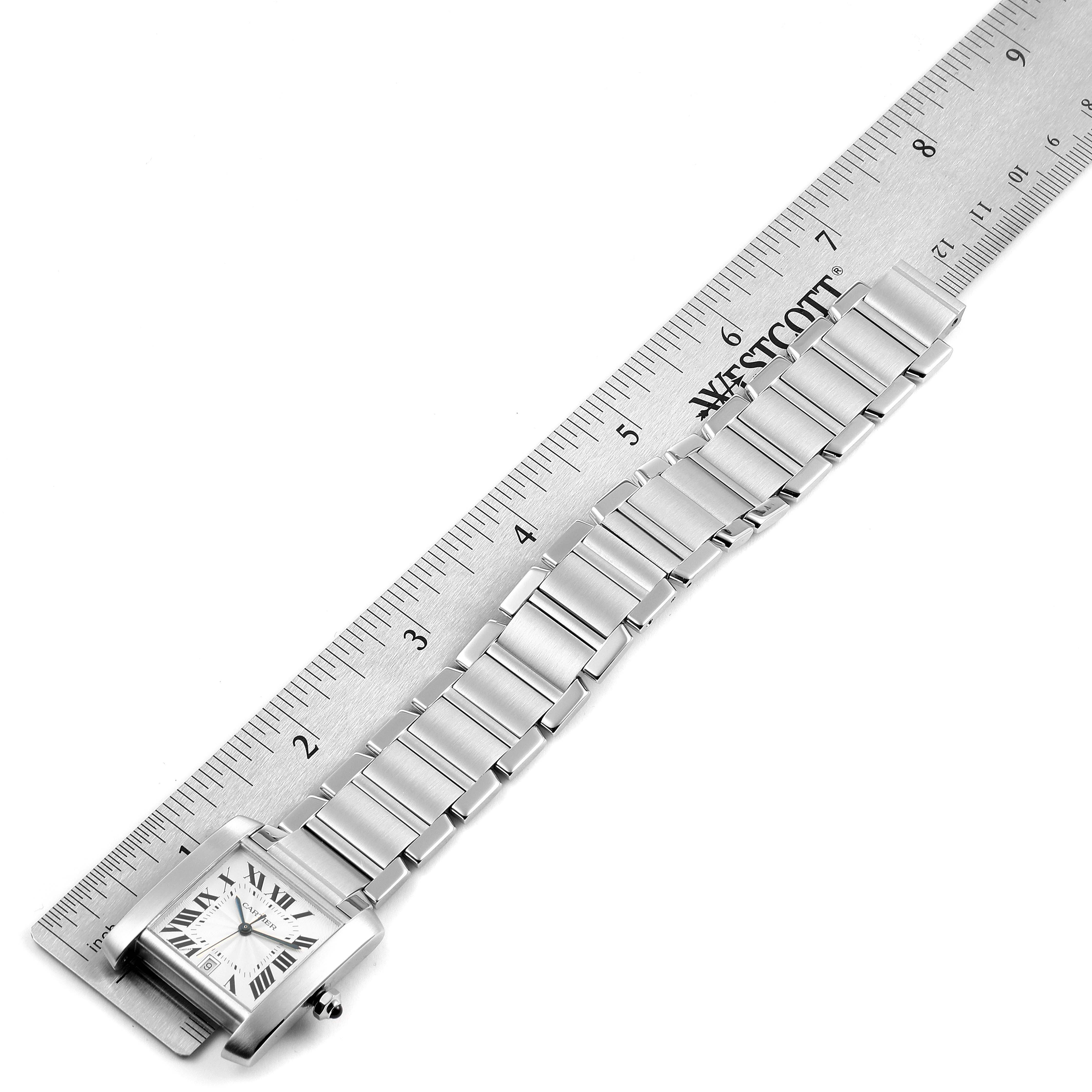 This image shows the Cartier Tank Francaise W51002Q3 Men's Stainless Steel Silver Dial W51002Q3 Men's Stainless Steel Silver Dial watch laid flat beside a ruler, highlighting its bracelet links and square face.