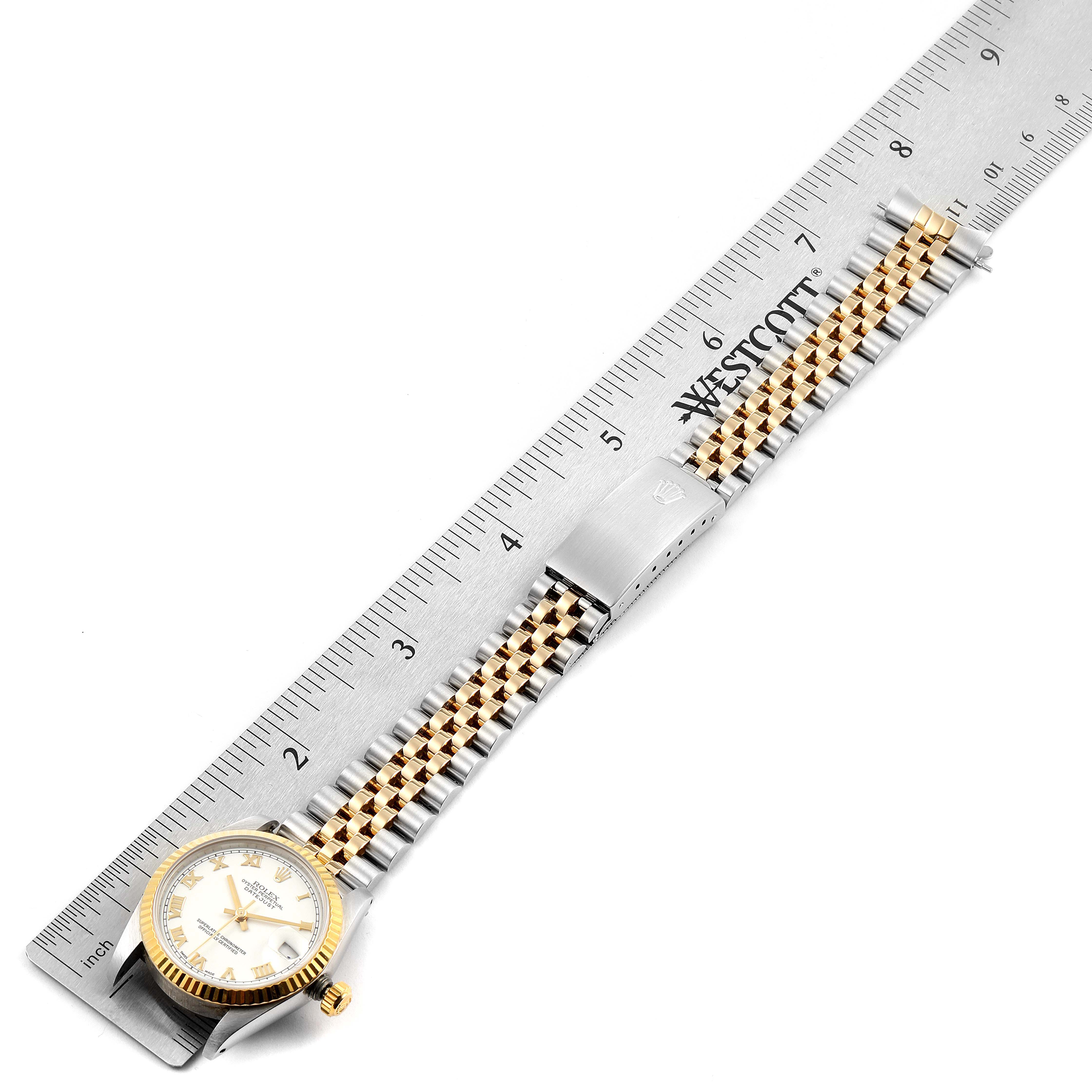 The Rolex Datejust 68273 Women's Steel and Gold (two tone) White Dial 68273 Women's Steel and Gold (two tone) White Dial watch is shown laid flat with its face and band fully extended next to a ruler.