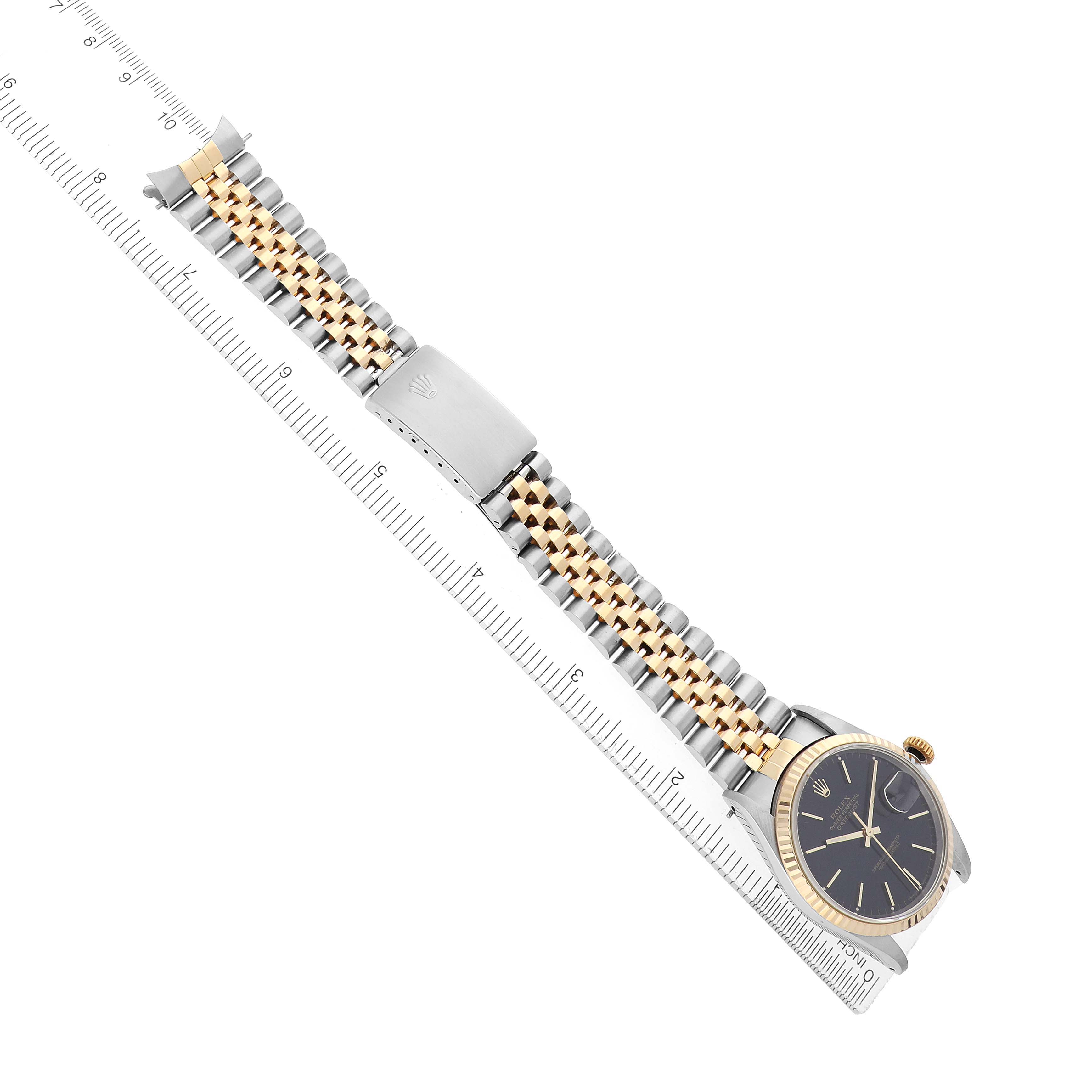 The image shows a Rolex Datejust 16233 Men's Steel and Gold (two tone) Black Dial watch laid diagonally, highlighting its bracelet and clasp beside a ruler for scale.