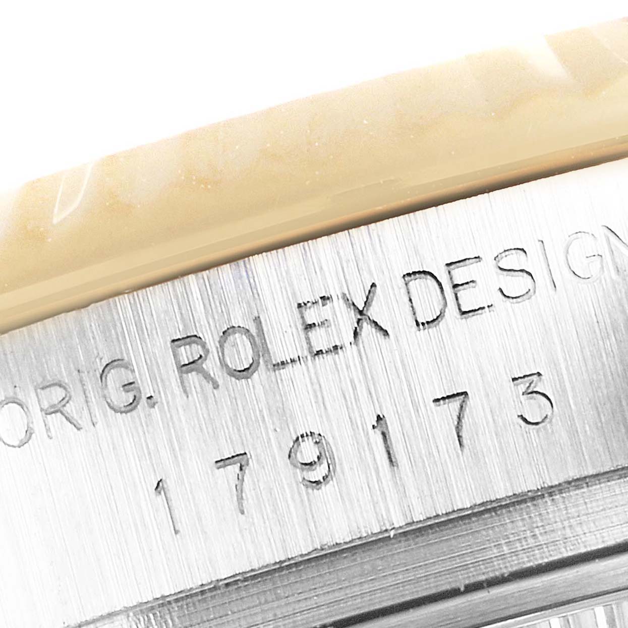 This close-up image shows the engraved serial number and "ROLEX DESIGN" text on the side of a Rolex Datejust 179173 Women's Steel and Gold (two tone) Black Dial 179173 Women's Steel and Gold (two tone) Black Dial watch case.