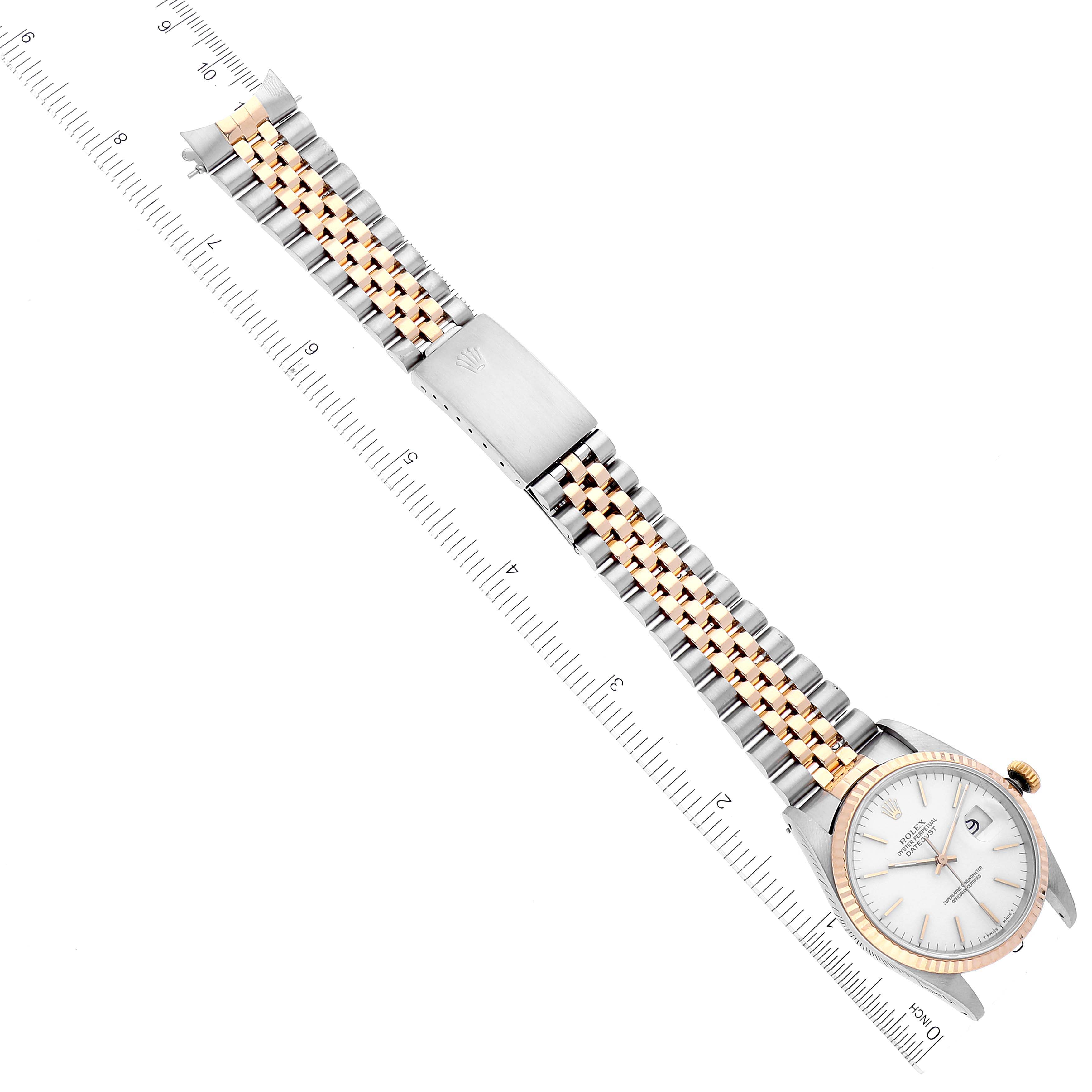 The image shows an overhead view of a Rolex Datejust 16233 Men's Steel and Gold (two tone) White Dial 16233 Men's Steel and Gold (two tone) White Dial watch with a two-tone bracelet and a ruler for scale.