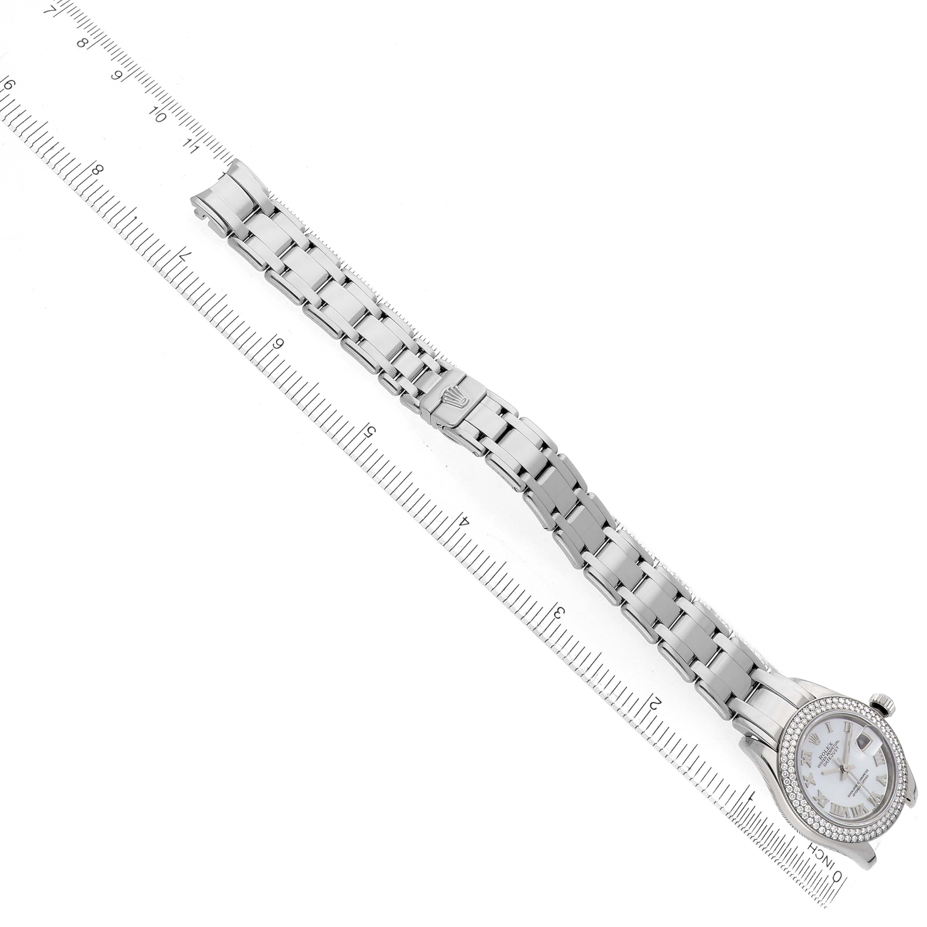 The Rolex Pearlmaster 80339 Women
s White Gold Mother of Pearl Dial watch is shown from a top-down angle, displaying the entire bracelet and face alongside a measuring scale.