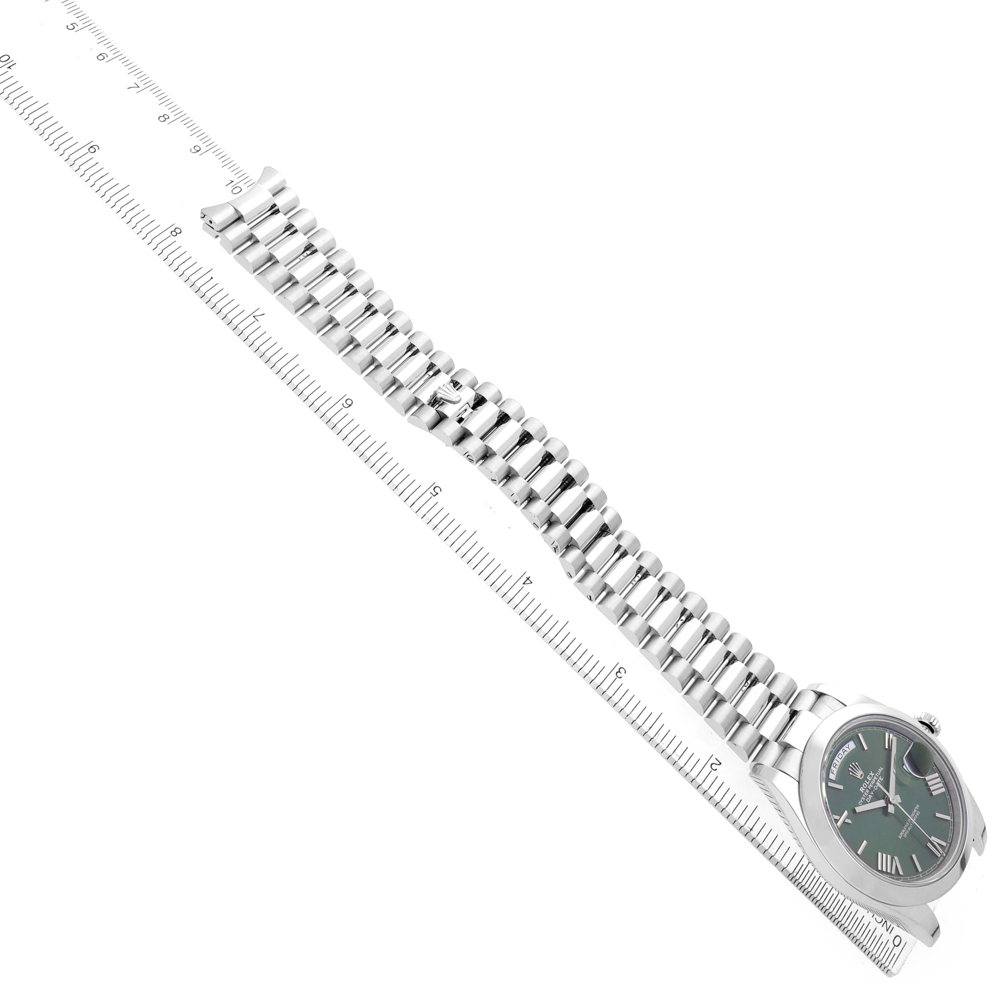 The image shows a Rolex President 228206 Men's Platinum Green Dial watch with a green dial and a silver bracelet, angled diagonally alongside a ruler.