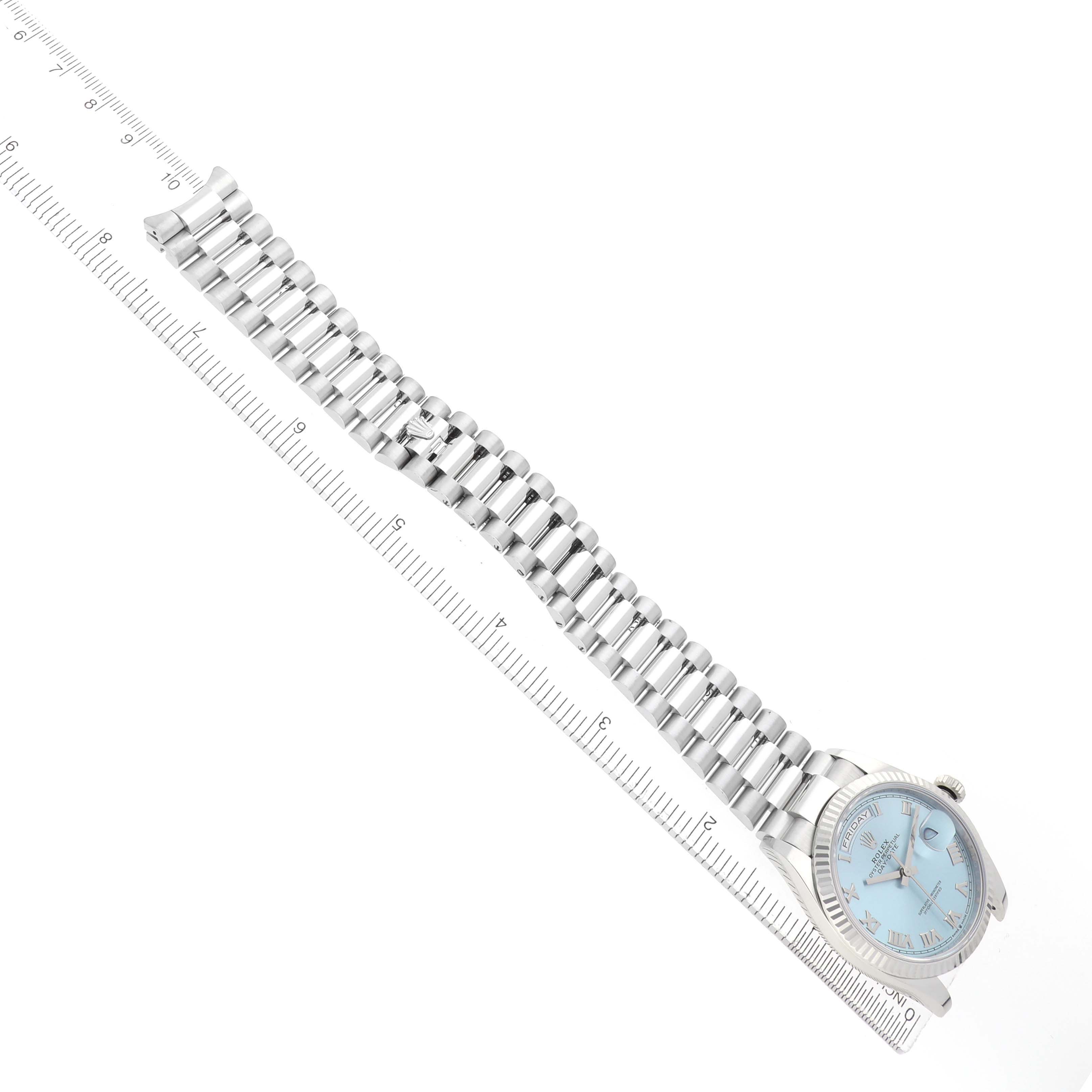 The Rolex President 128236 Men's Platinum Blue Dial watch is shown at an angle displaying the bracelet and face, positioned alongside a ruler for scale.