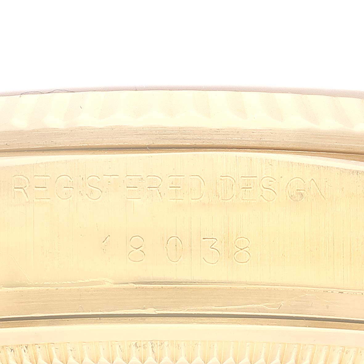 This image shows a close-up of the side of a Rolex President 18038 Men
s Yellow Gold Champagne Dial 18038 Men
s Yellow Gold Champagne Dial model watch, highlighting the engraved "REGISTERED DESIGN 18038."