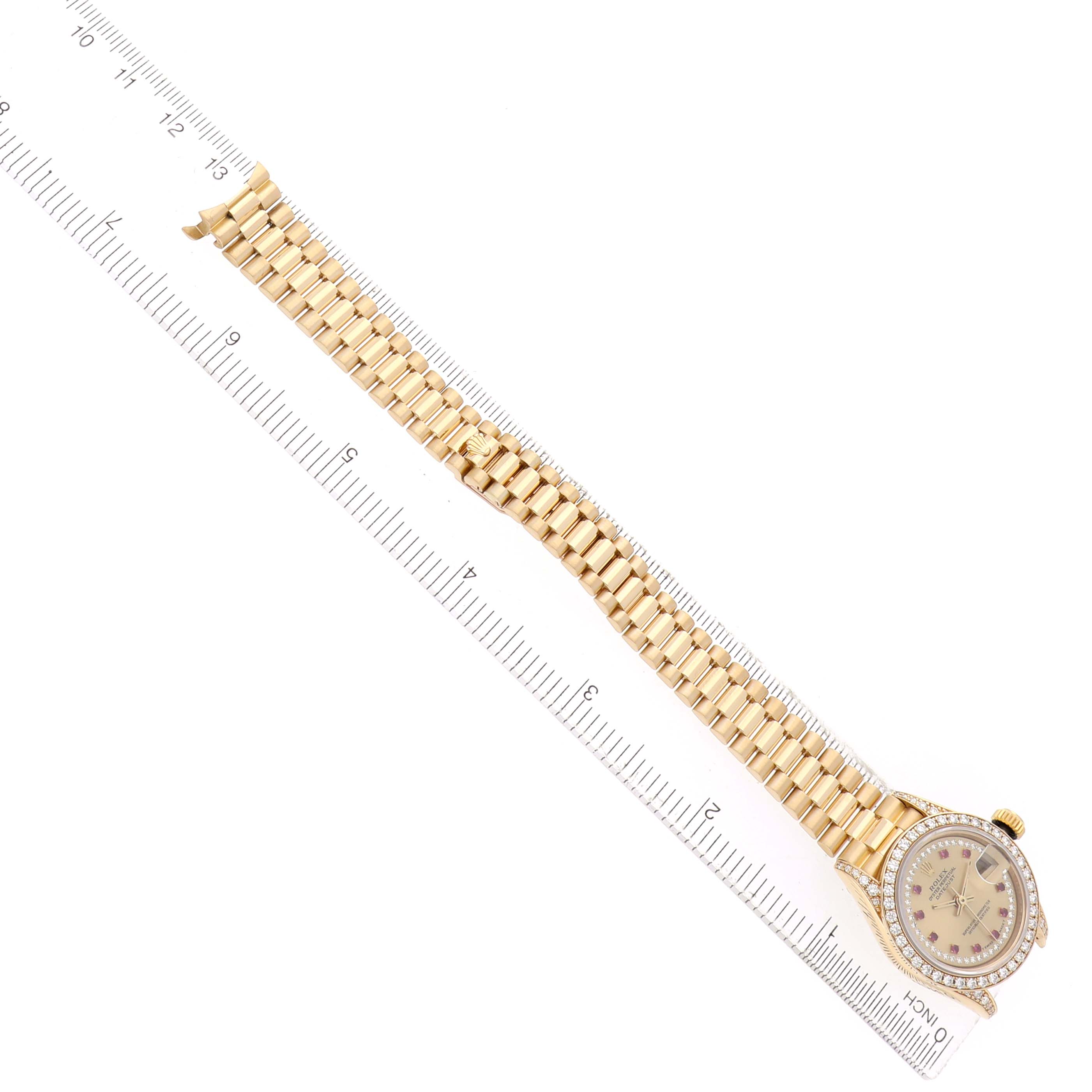 The Rolex President 69158 Women's Yellow Gold Champagne Dial model watch is shown from an overhead angle, displaying the full face, bracelet, and a ruler for scale.