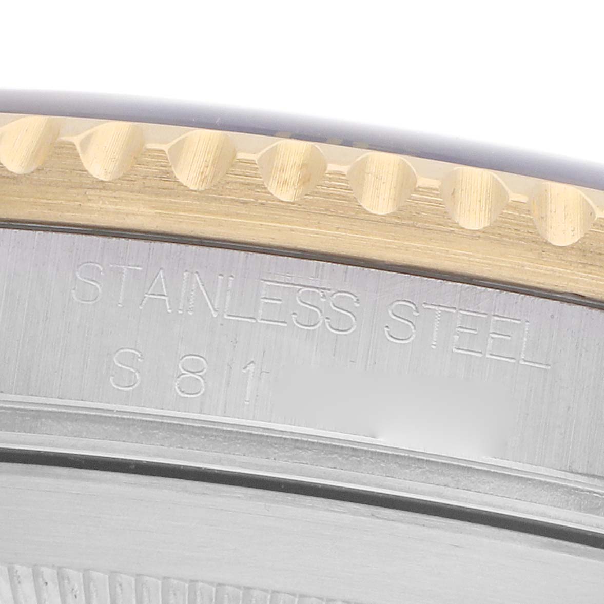 The image shows a close-up of the Rolex Submariner 16613 Men's Steel and Gold (two tone) Blue Dial's bezel edge and part of the stainless steel case with engraved text.