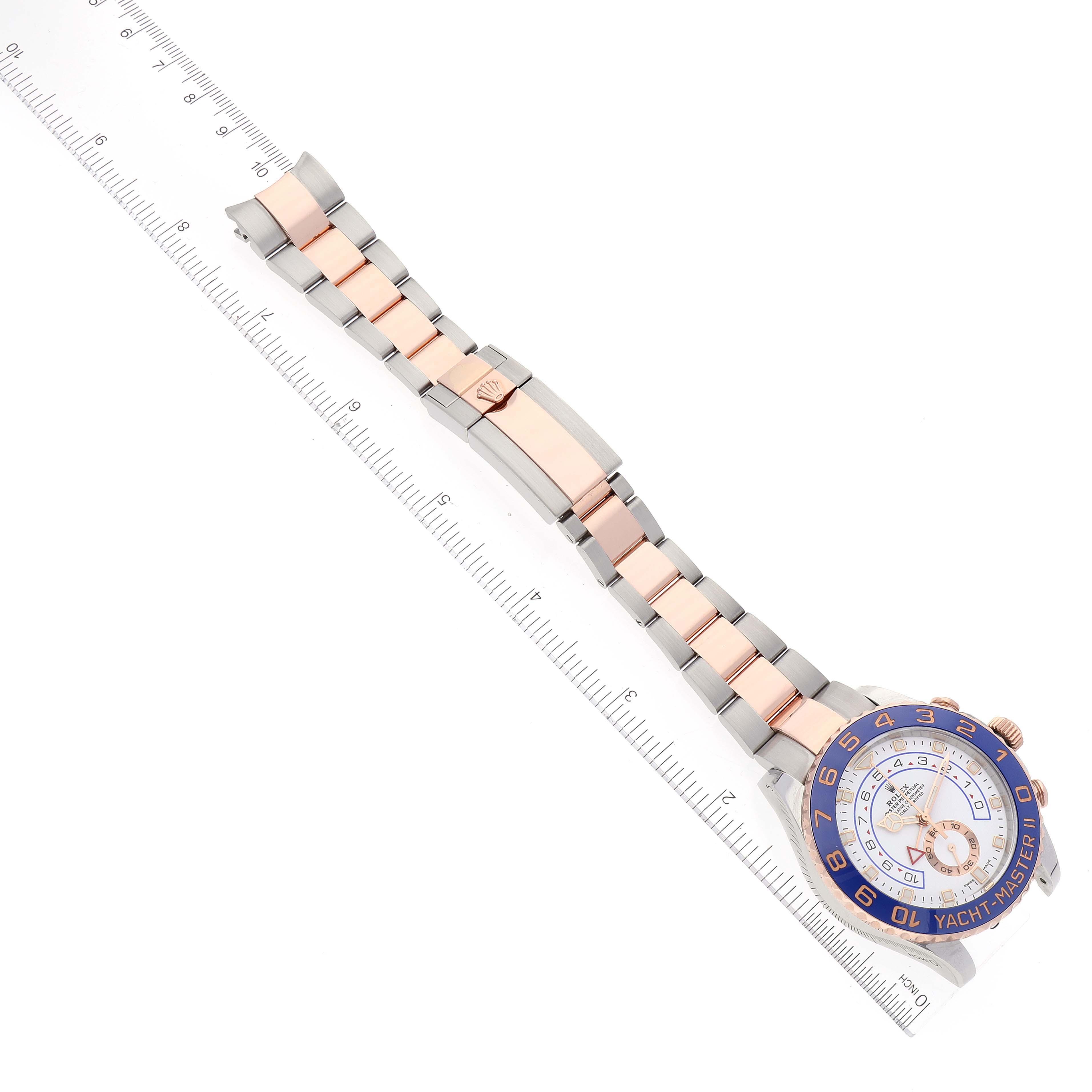 The image shows a full-length view of a Rolex Yacht-Master 116681 Men
s Steel and Gold (two tone) White Dial 116681 Men
s Steel and Gold (two tone) White Dial watch, including the face, bezel, bracelet, and clasp, placed next to rulers.