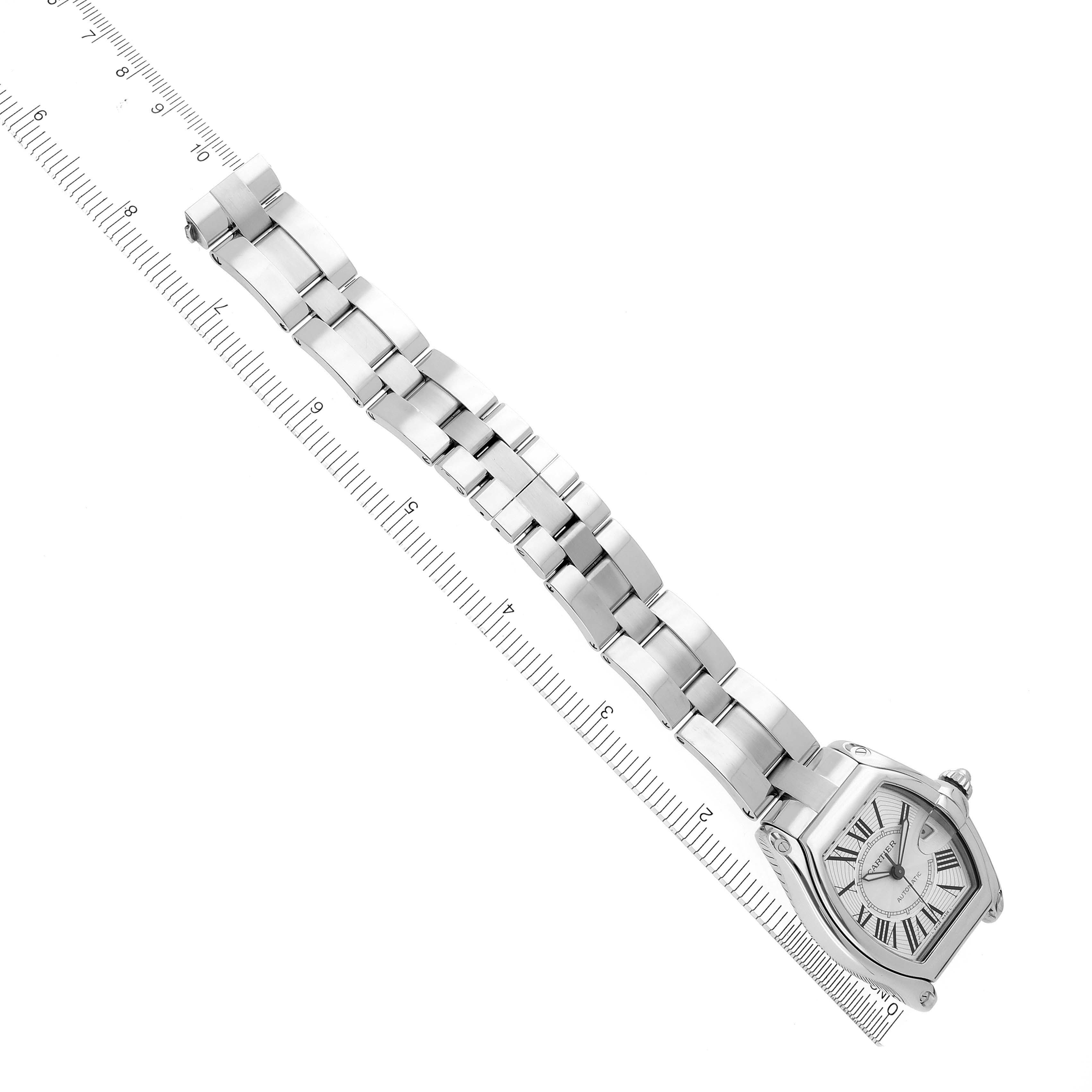 The Cartier Roadster W62025V3 Men's Stainless Steel Silver Dial W62025V3 Men's Stainless Steel Silver Dial watch is shown from a top-down angle, featuring its full bracelet and face alongside a ruler for scale.