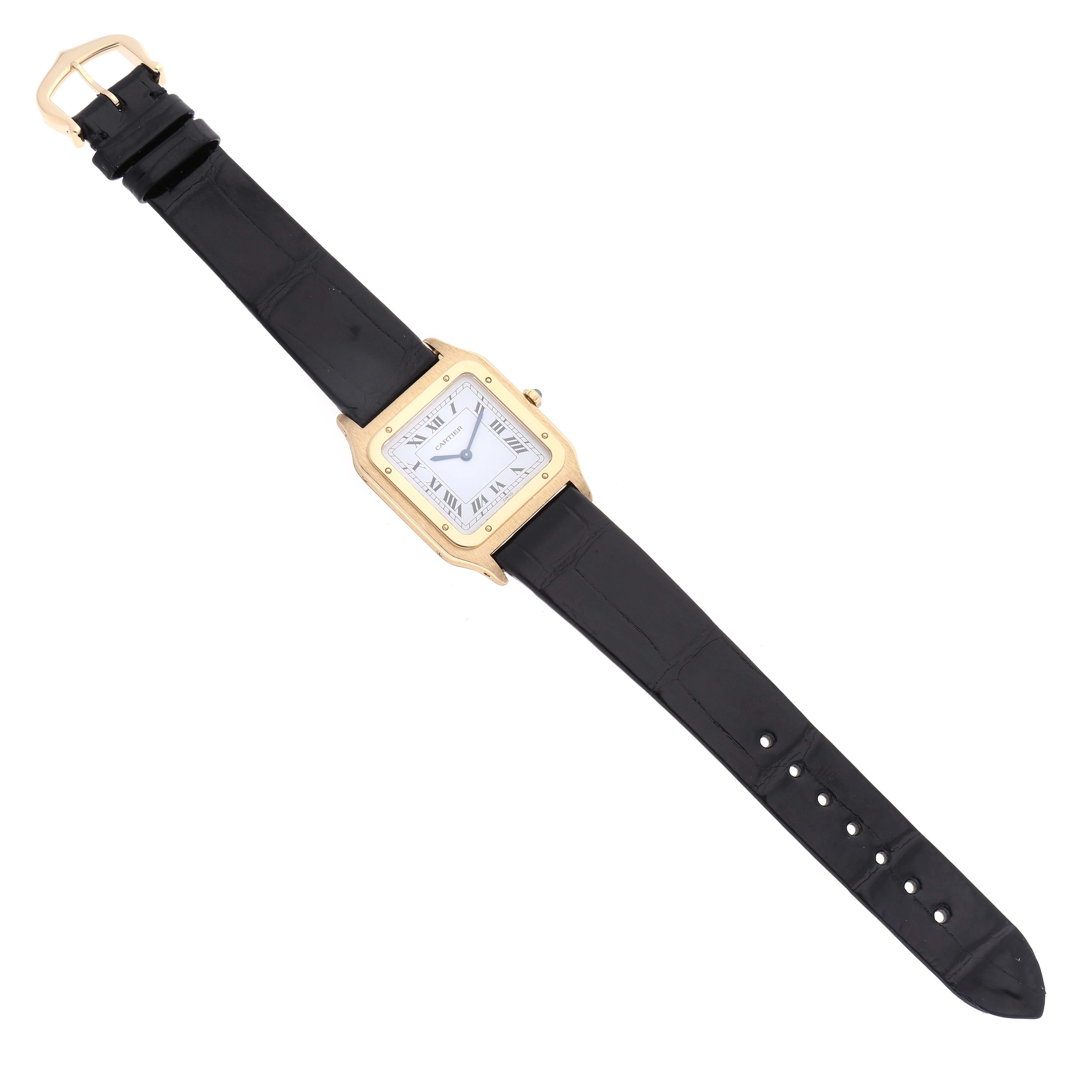 The Cartier Santos Dumont 15751 Men's Yellow Gold White Dial 15751 Men's Yellow Gold White Dial watch is shown from a top view, highlighting its square face, black strap, and gold-tone case.
