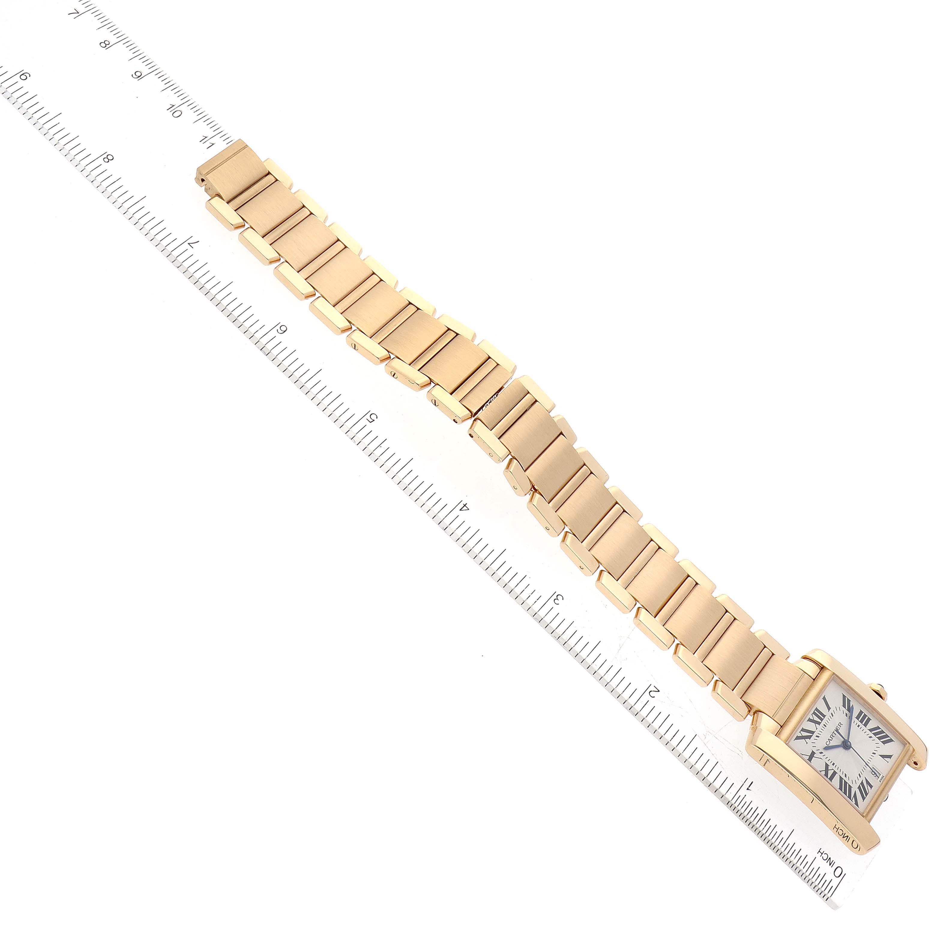 The image shows a side angle of the Cartier Tank Francaise W50001R2 Men
s Yellow Gold Silver Dial W50001R2 Men
s Yellow Gold Silver Dial watch focusing on its gold bracelet and partial face, along with a ruler for scale.