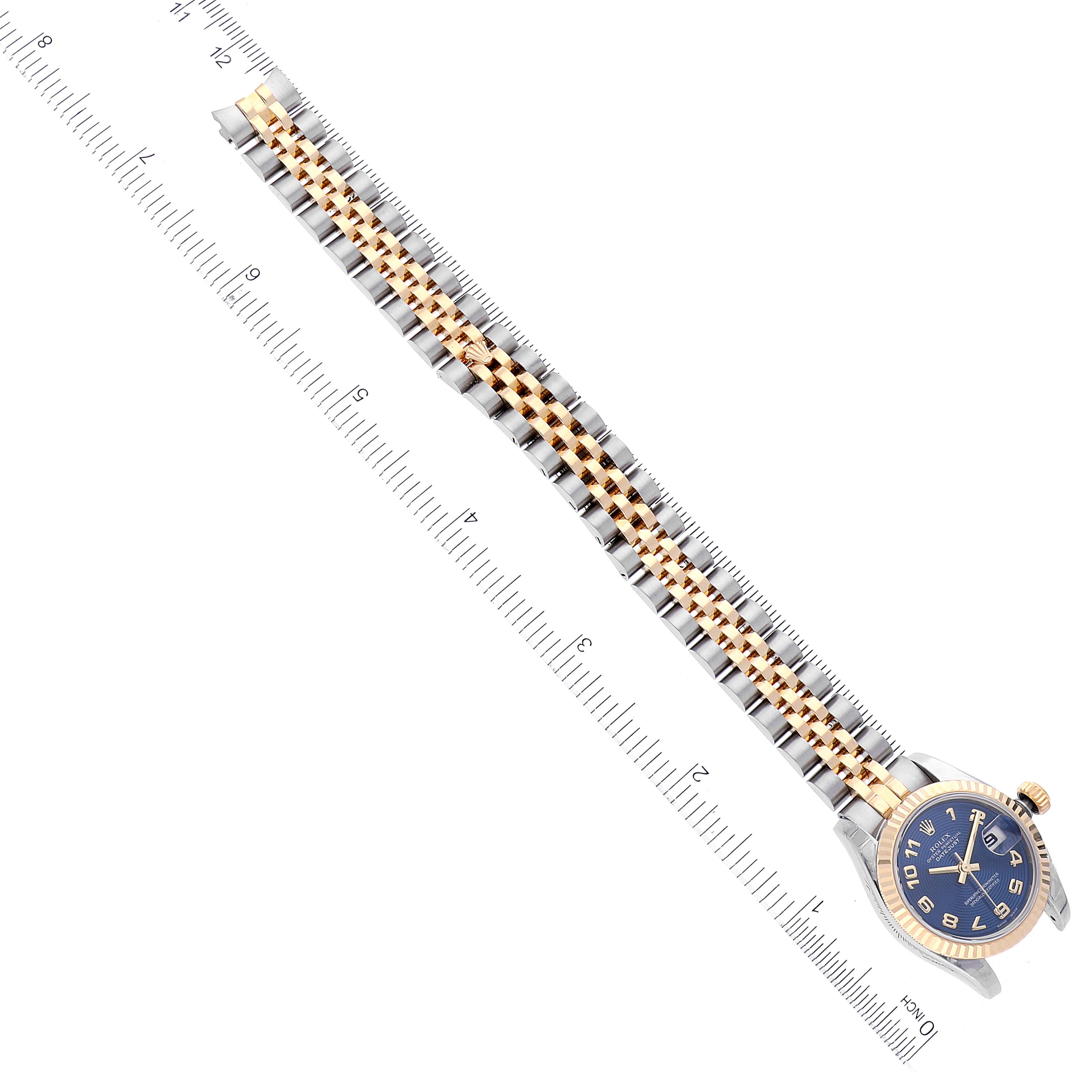 This image shows a Rolex Datejust 179173 Women's Steel and Gold (two tone) Blue Dial 179173 Women's Steel and Gold (two tone) Blue Dial watch laid flat with a two-tone band and the dial pointing to the right, next to a measuring ruler.