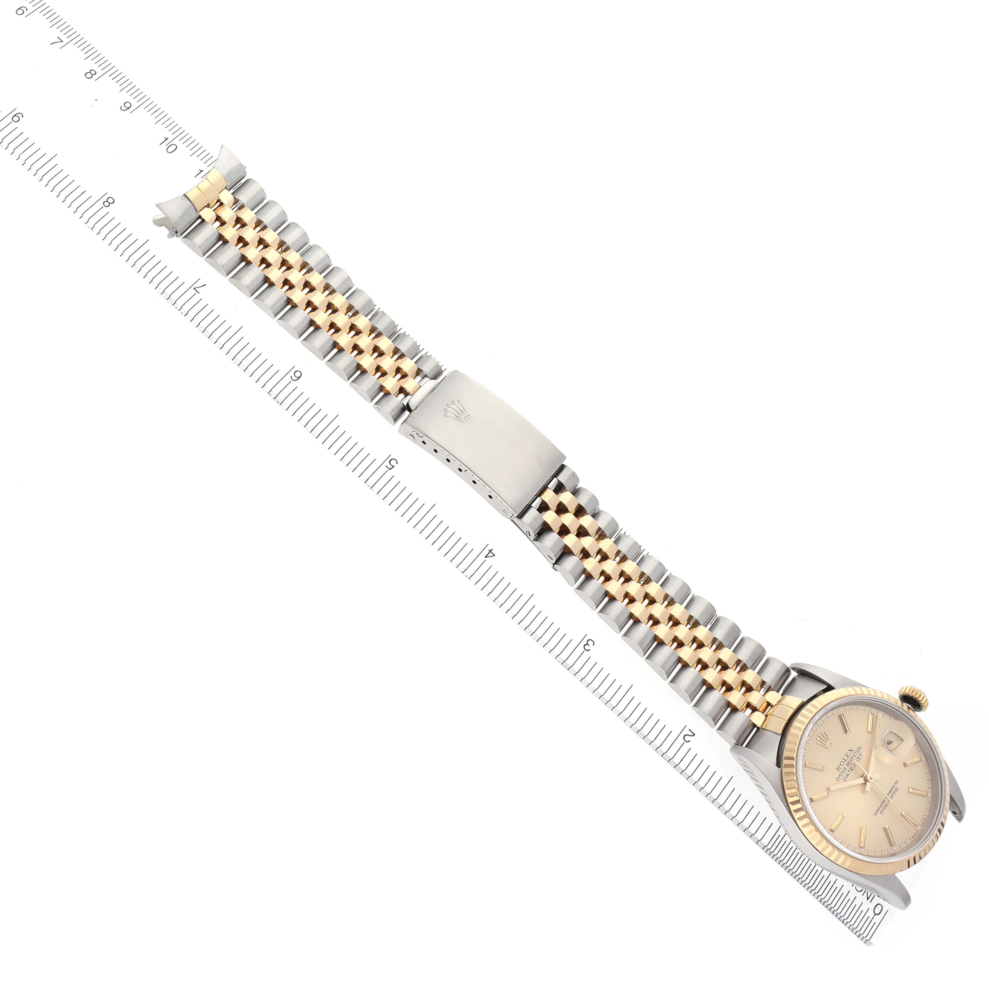 The Rolex Datejust 16233 Men's Steel and Gold (two tone) Champagne Dial 16233 Men's Steel and Gold (two tone) Champagne Dial watch is shown at an angled view with the face, bracelet, and clasp visible alongside a measuring scale.