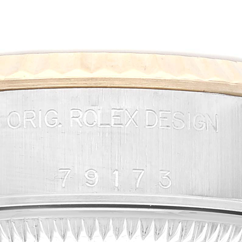 This close-up image shows the side of a Rolex Datejust 79173 Women's Steel and Gold (two tone) Champagne Dial 79173 Women's Steel and Gold (two tone) Champagne Dial watch case with the engravings "ORIG. ROLEX DESIGN" and "79173".