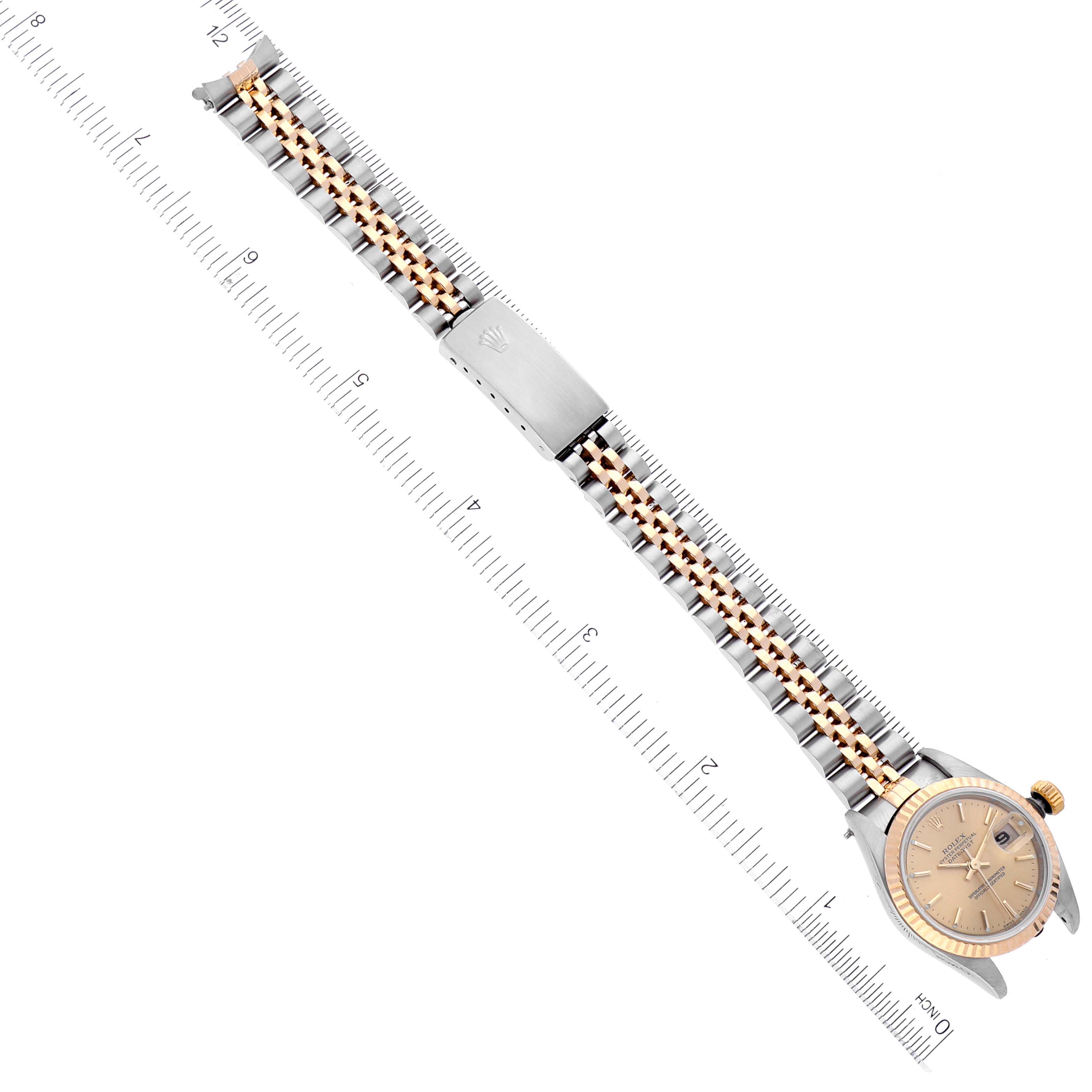 The image shows an overhead view of the Rolex Datejust 79173 Women's Steel and Gold (two tone) Champagne Dial 79173 Women's Steel and Gold (two tone) Champagne Dial watch, highlighting its bracelet, clasp, and face alongside a ruler for scale.