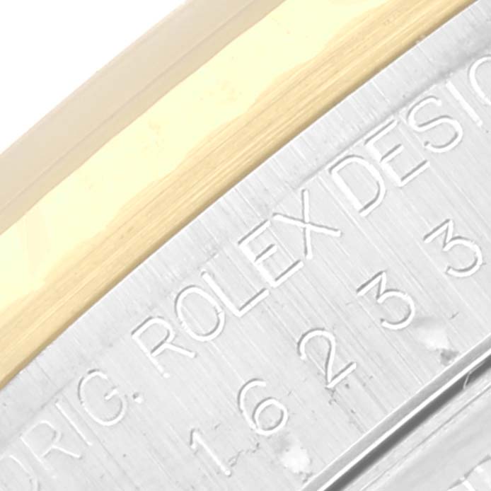 The close-up image shows the engraved text “Rolex Design” and part of the bezel on a Datejust model by Rolex.