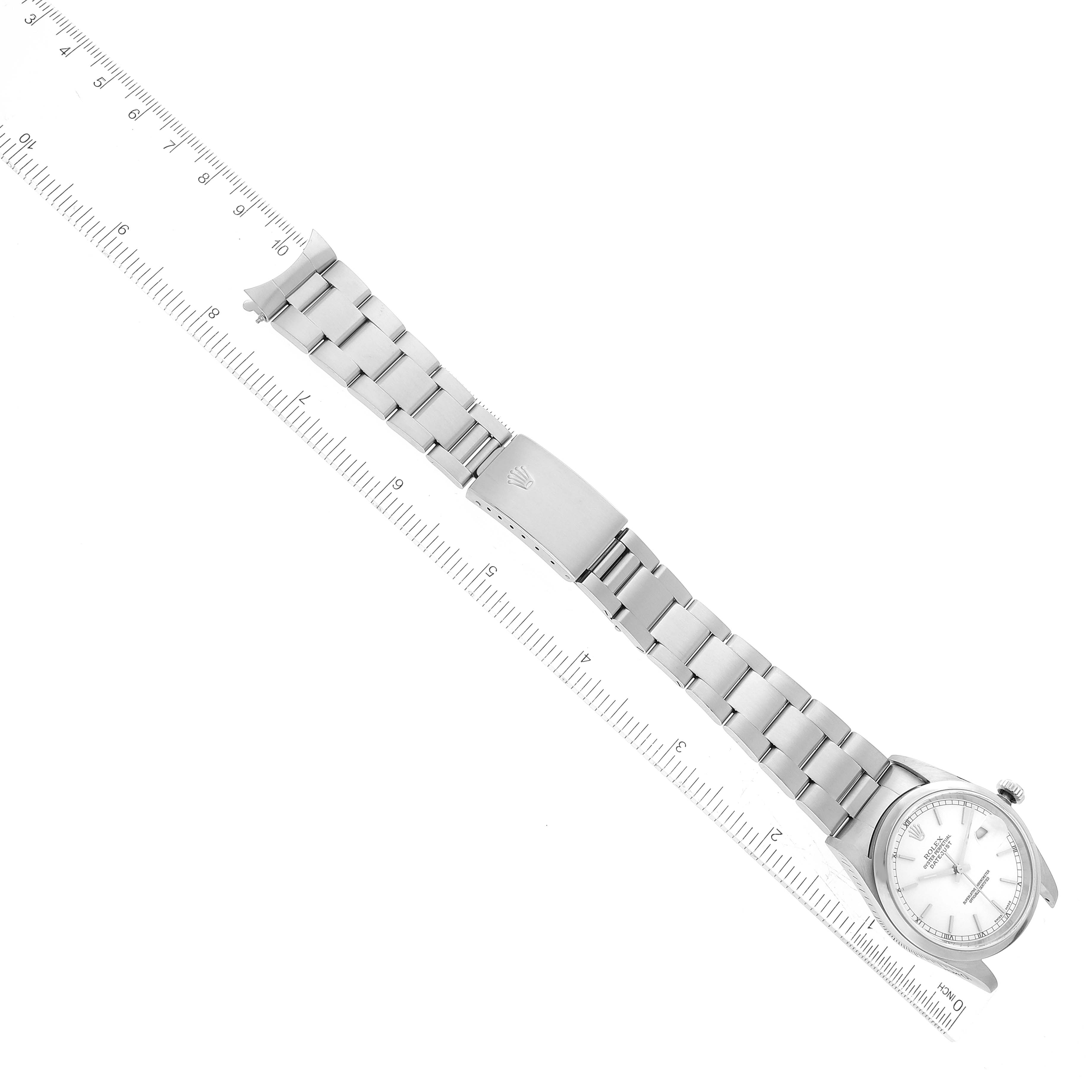 The image shows a top-down view of a Rolex Datejust 16200 Men's Stainless Steel White Dial 16200 Men's Stainless Steel White Dial watch with a ruler for scale, displaying its dial, bracelet, and clasp.