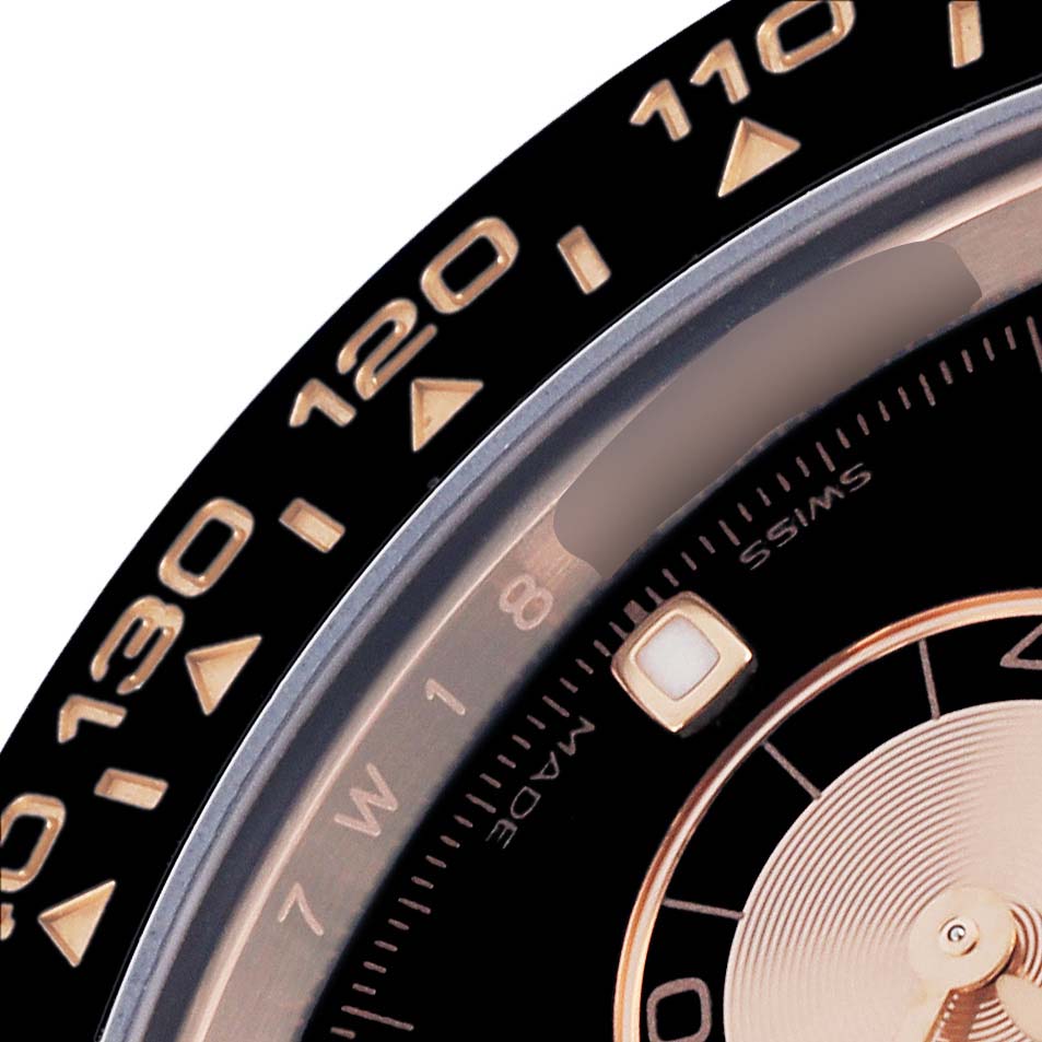 The image shows a close-up of the Rolex Daytona 116515 Men's Rose Gold Black Dial 116515 Men's Rose Gold Black Dial's bezel and part of the dial with tachymetric scale.