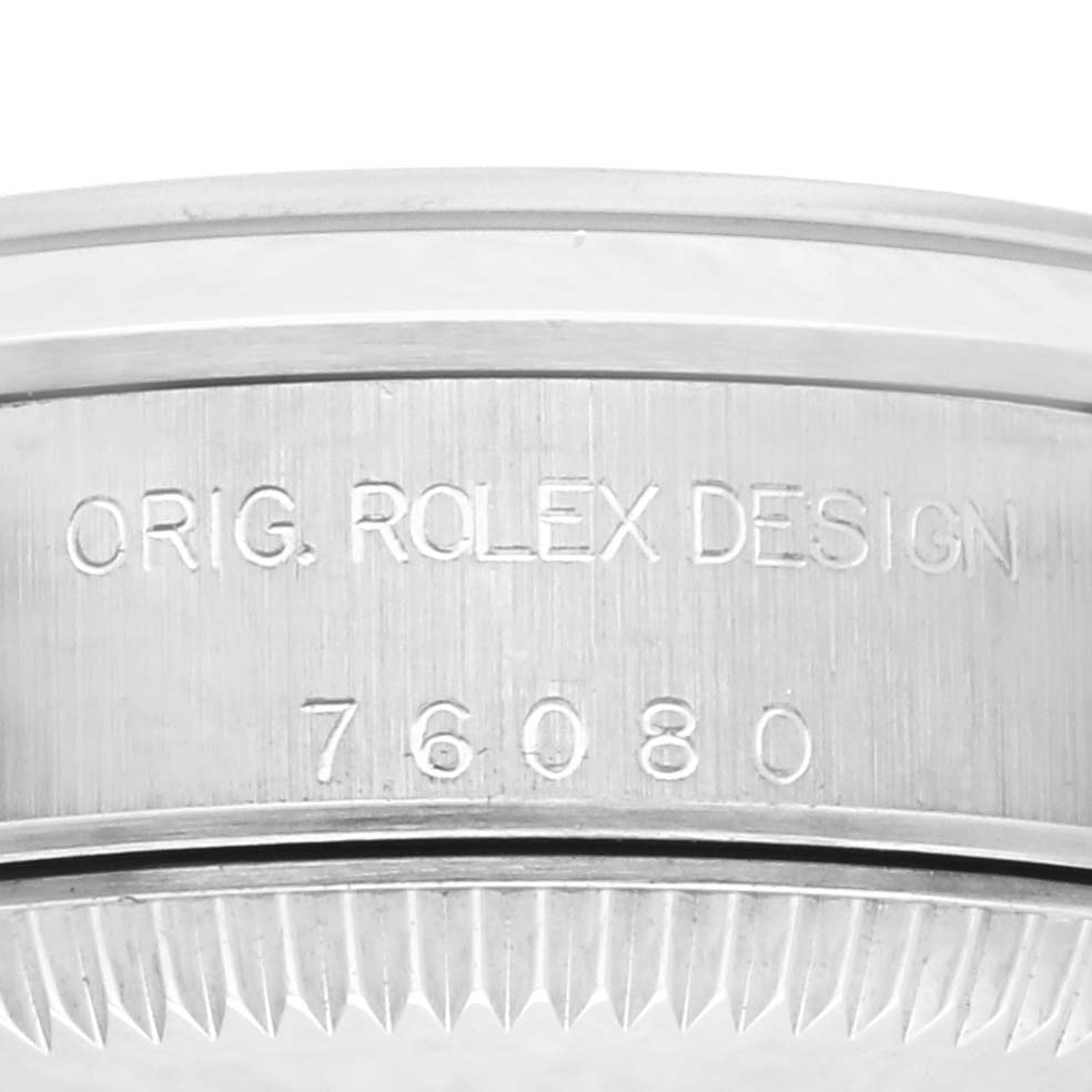 The image shows the side of a Rolex Oyster Perpetual 76080 Women's Stainless Steel Pink Dial 76080 Women's Stainless Steel Pink Dial watch, focusing on the engraved design and model number.