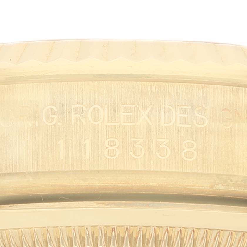 The image shows a close-up of the side view of a Rolex President 118338 Men
s Yellow Gold  118338 Men
s Yellow Gold  model with the engraving "ROLEX DES" and model number 118338.