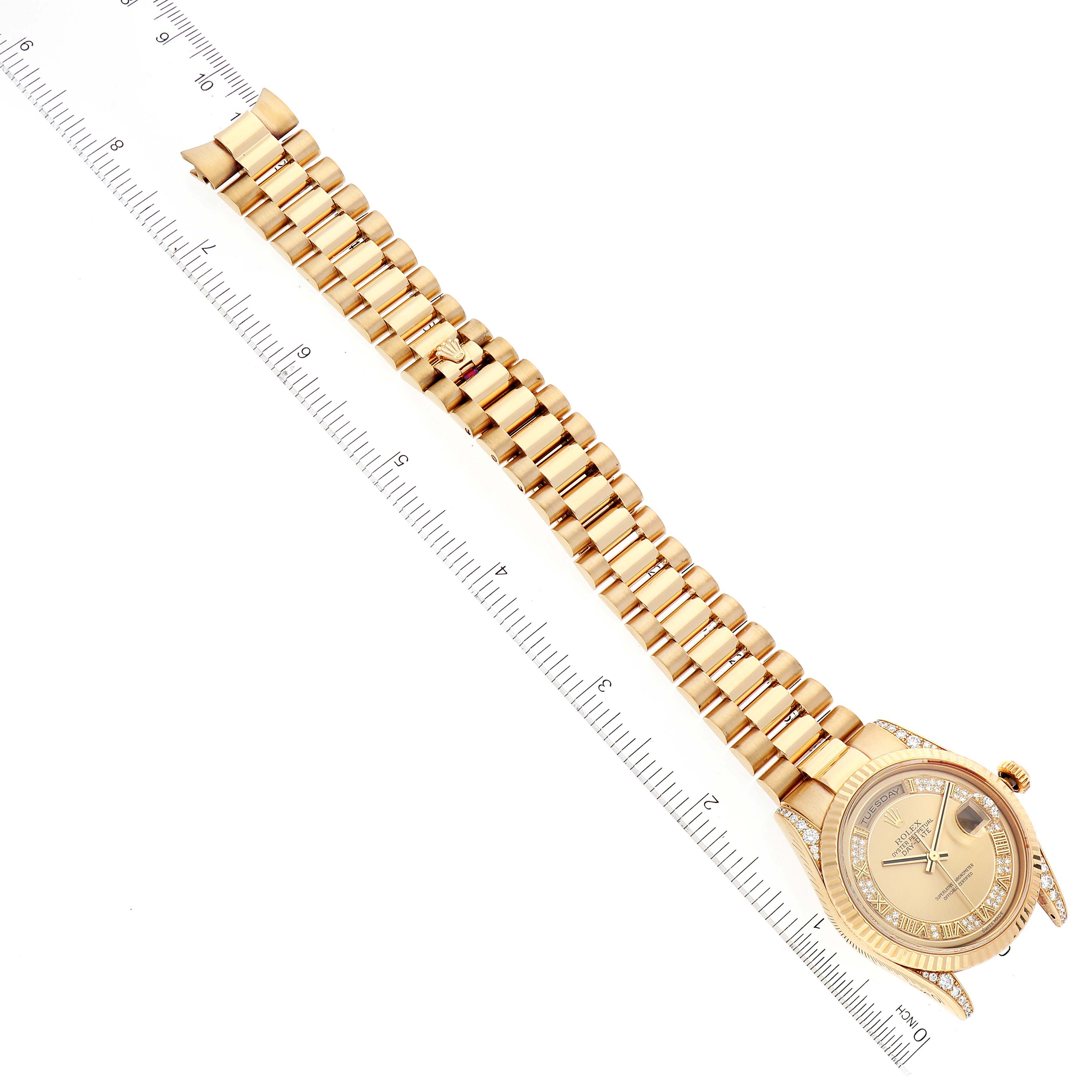 This image shows the face and gold bracelet of the Rolex President 118338 Men
s Yellow Gold  118338 Men
s Yellow Gold  model watch placed next to a ruler for scale.