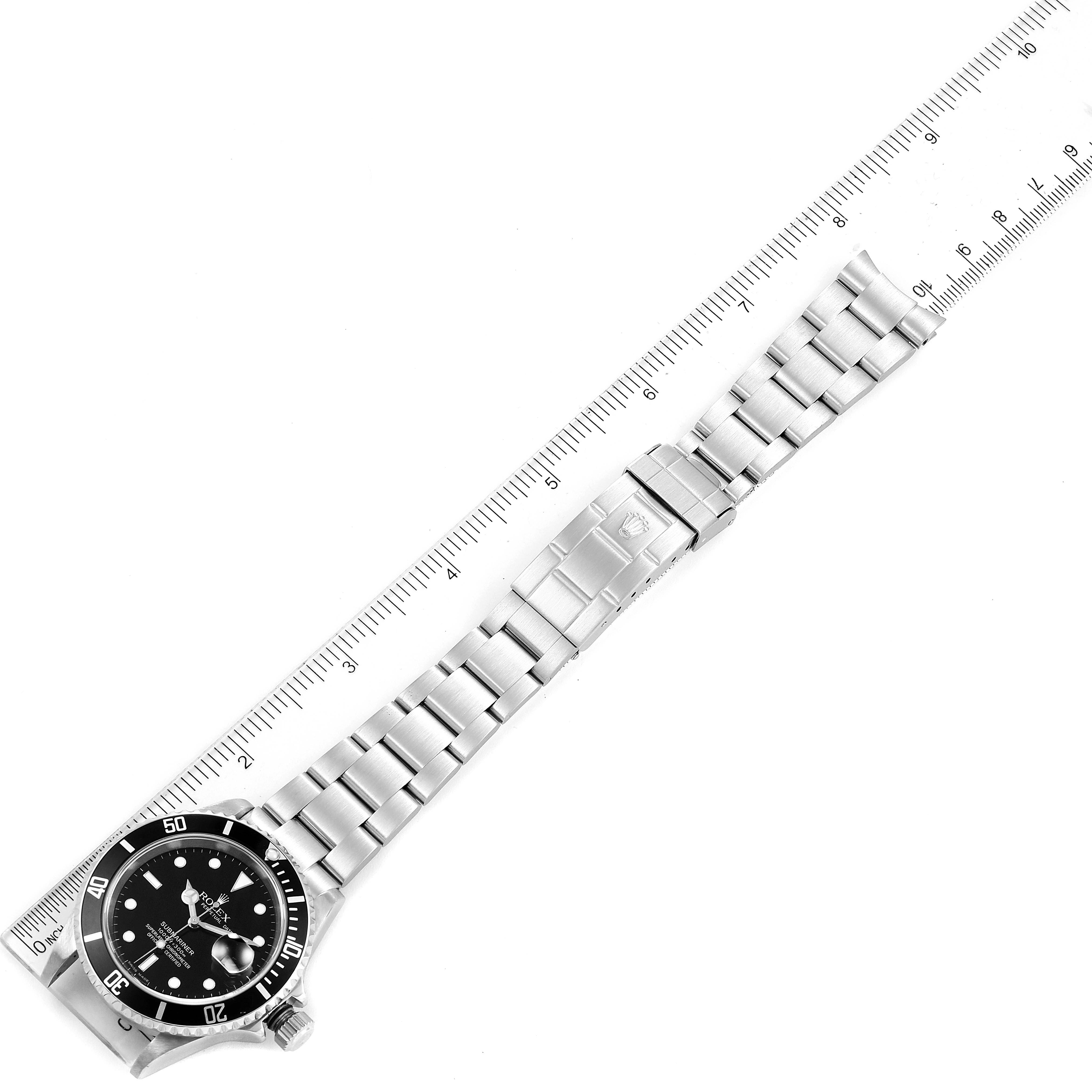 The image shows a Rolex Submariner 16610 Men's Stainless Steel Black Dial 16610 Men's Stainless Steel Black Dial watch laid flat with a stainless steel bracelet, alongside a ruler for scale.