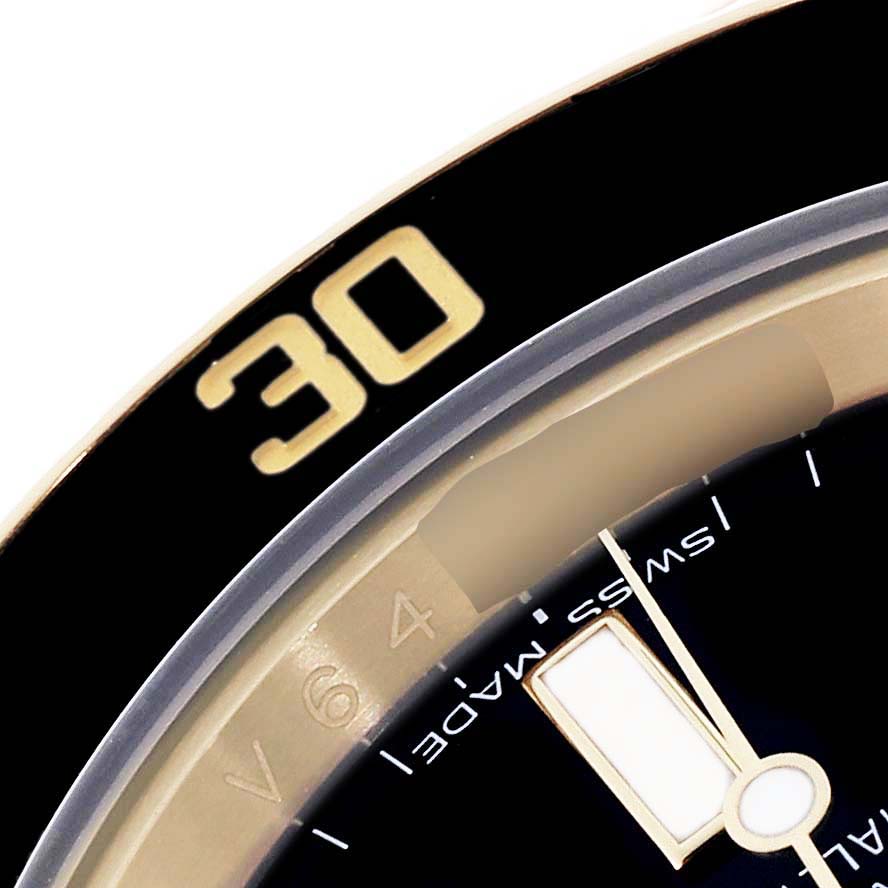 The image shows the bezel and part of the dial of the Rolex Submariner 116618 Men's Yellow Gold Black Dial 116618 Men's Yellow Gold Black Dial watch from a close-up angle.