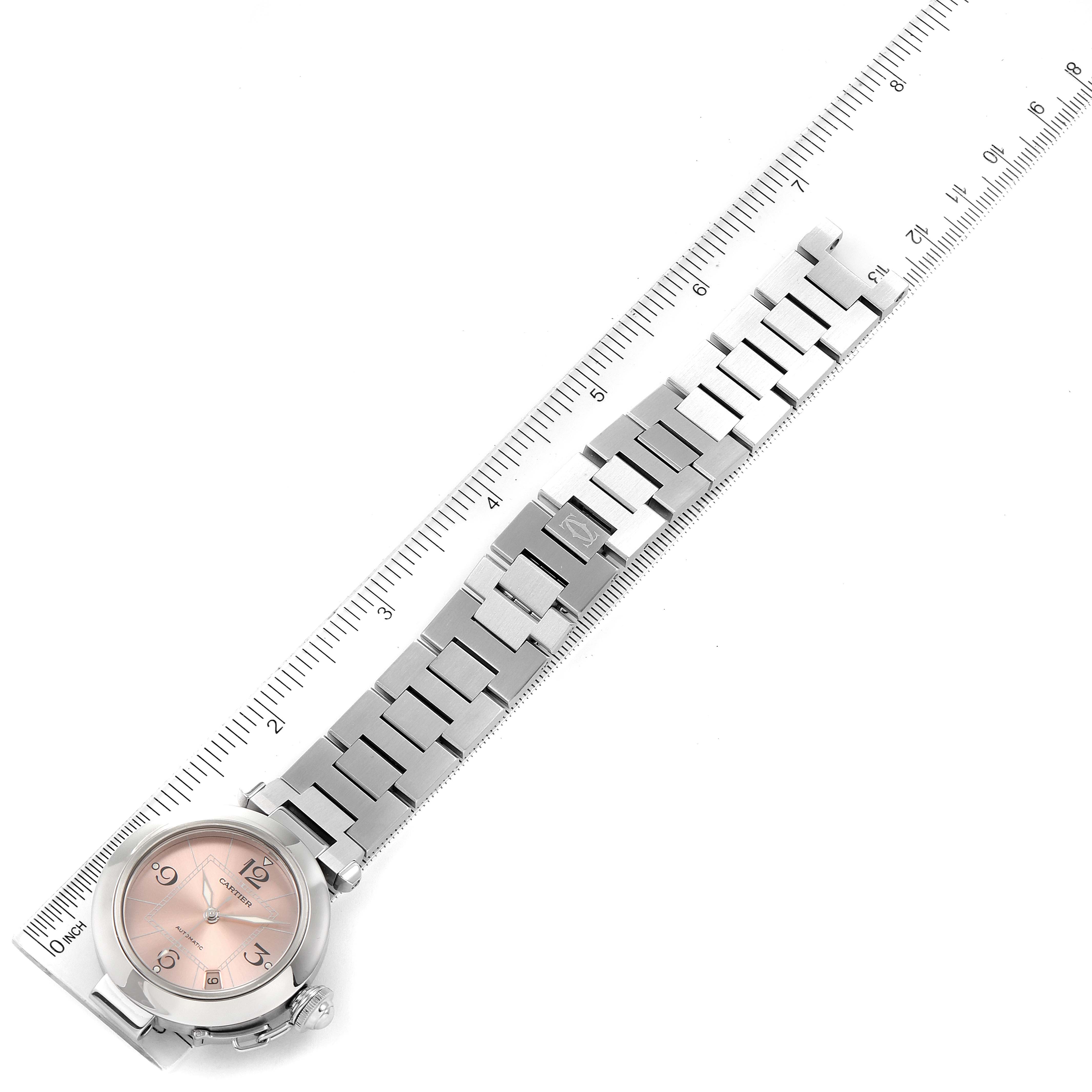 This image shows the Cartier Pasha W31075M7 Women's Stainless Steel Pink Dial W31075M7 Women's Stainless Steel Pink Dial watch laid flat with a ruler for measurement, highlighting its face, bezel, and bracelet.