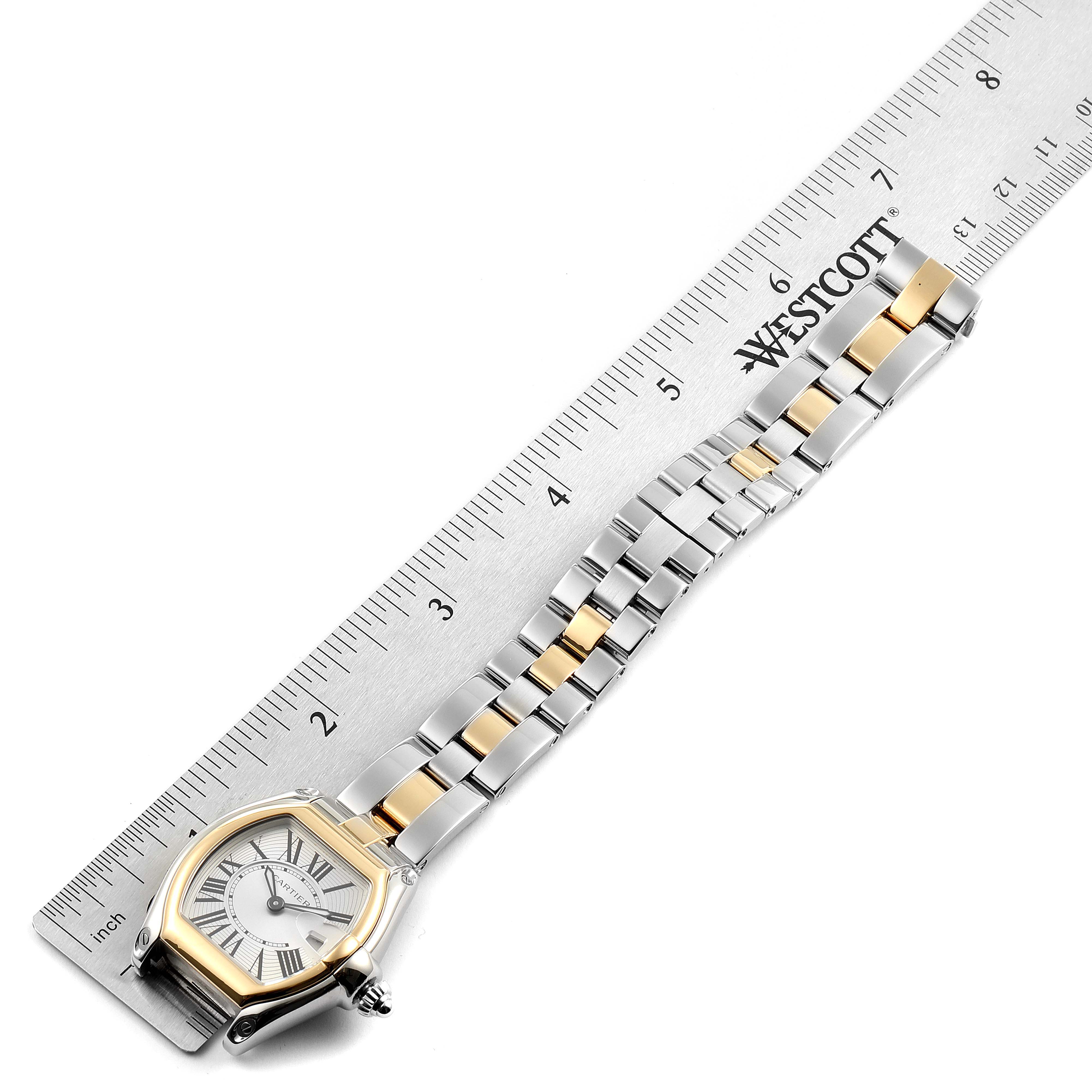 The image shows a top-down view of a Cartier Roadster W62026Y4 Women
s Steel and Gold (two tone) Silver Dial W62026Y4 Women
s Steel and Gold (two tone) Silver Dial watch with a ruler for scale, highlighting the face and bracelet.